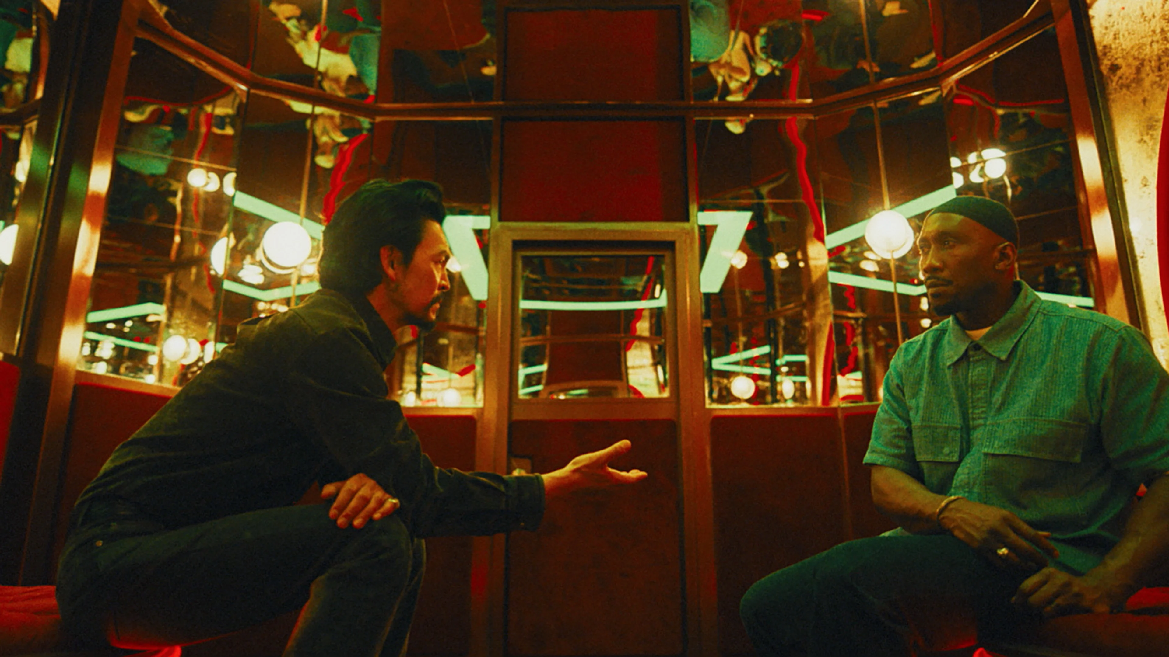 John Cho as Hwan Yoon faces Mahershala Ali as Latif inside a lit room.
