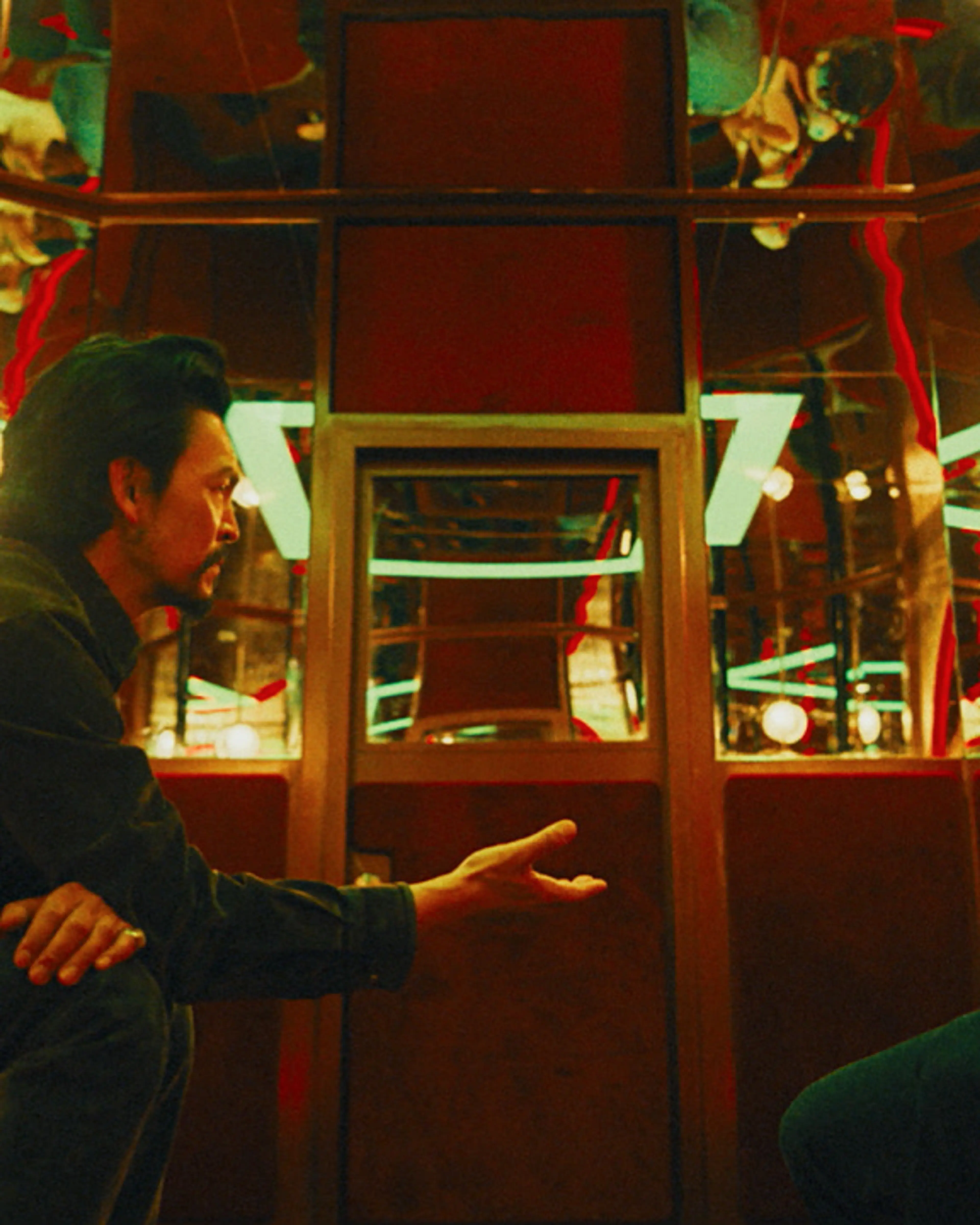 John Cho as Hwan Yoon faces Mahershala Ali as Latif inside a lit room.