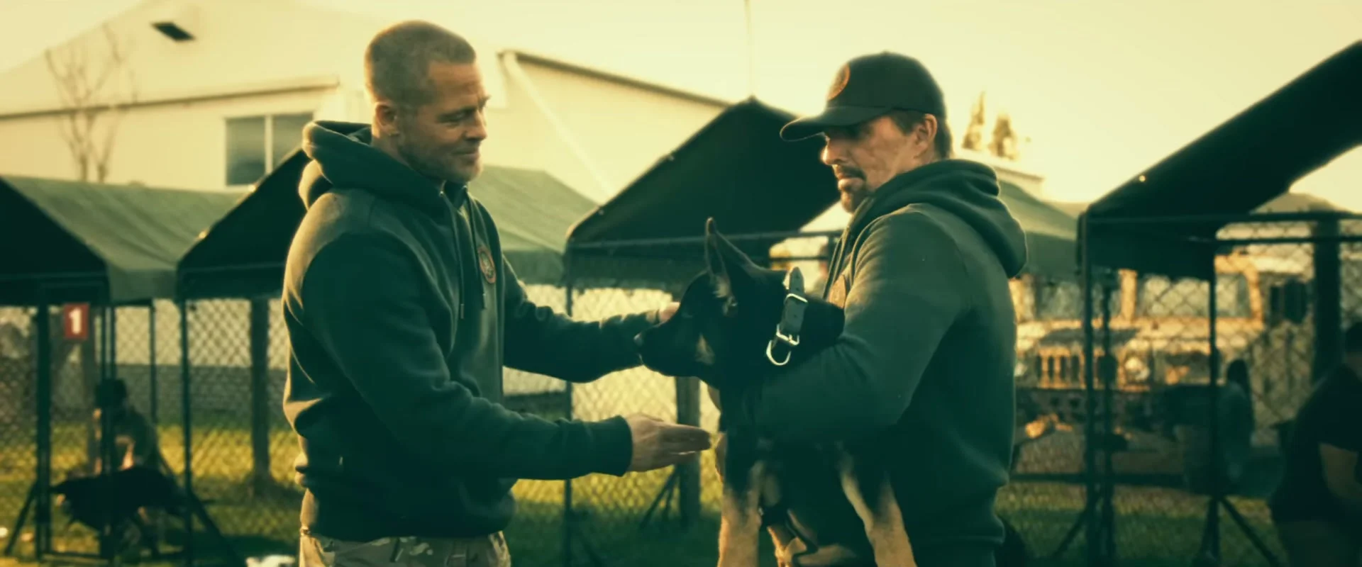 Brad Pitt stands beside a trainer holding the dog who plays Odin in Heart of the Beast.
