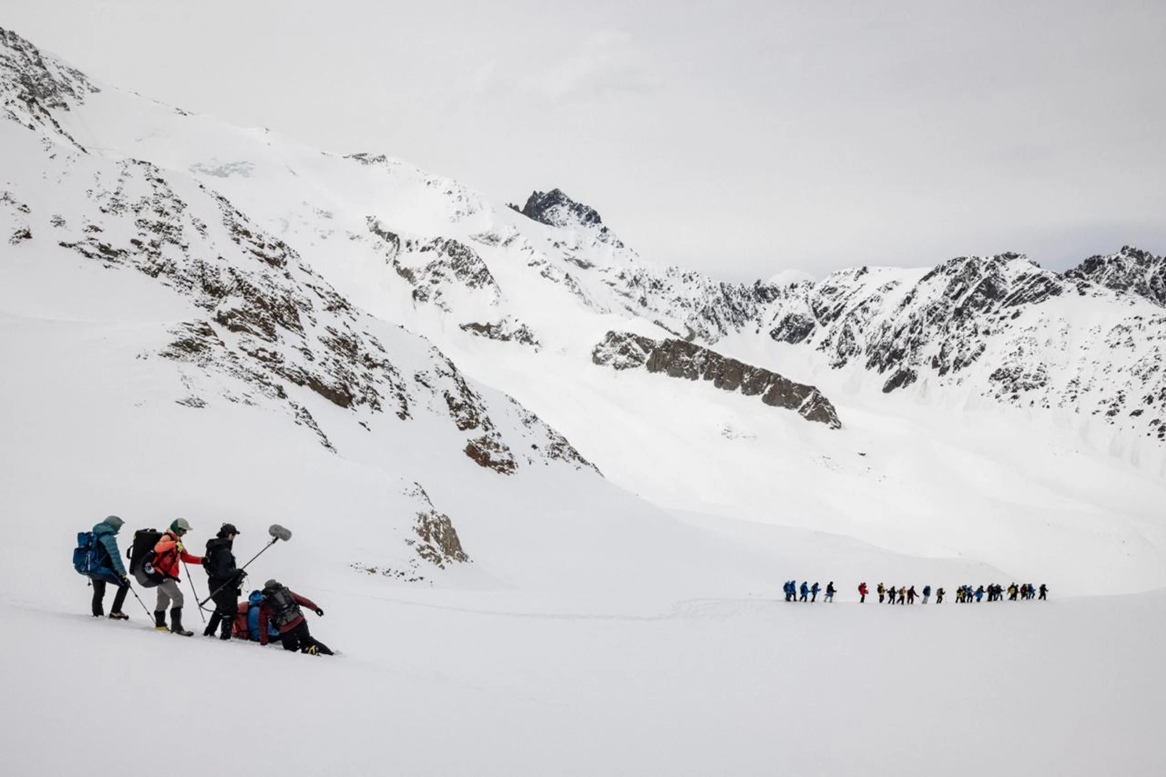 People and a film crew cross a broad snow-covered Andes landscape during production of Beyond Society.