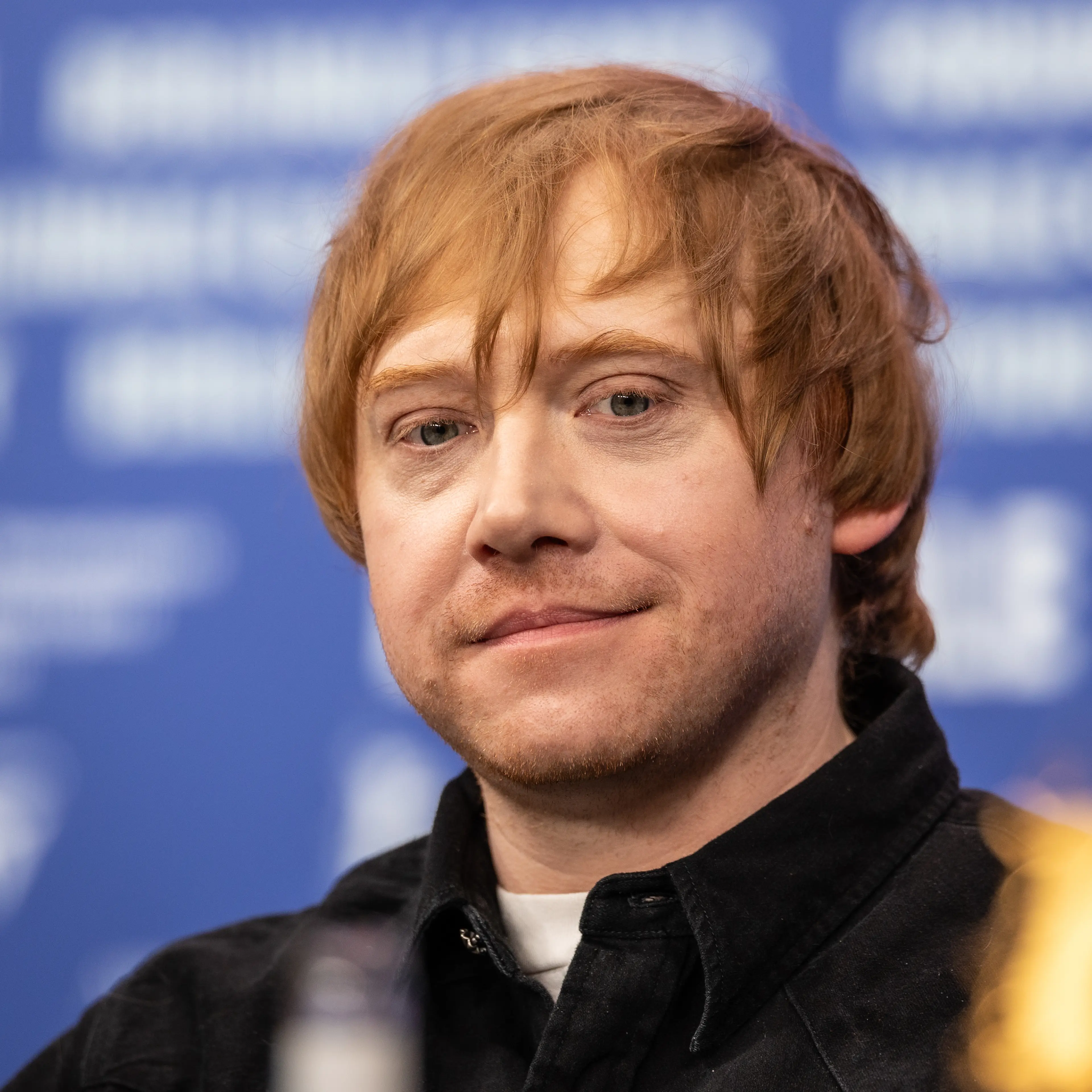 Rupert Grint with red hair and a black shirt at a Berlin International Film Festival press conference in February 2026.