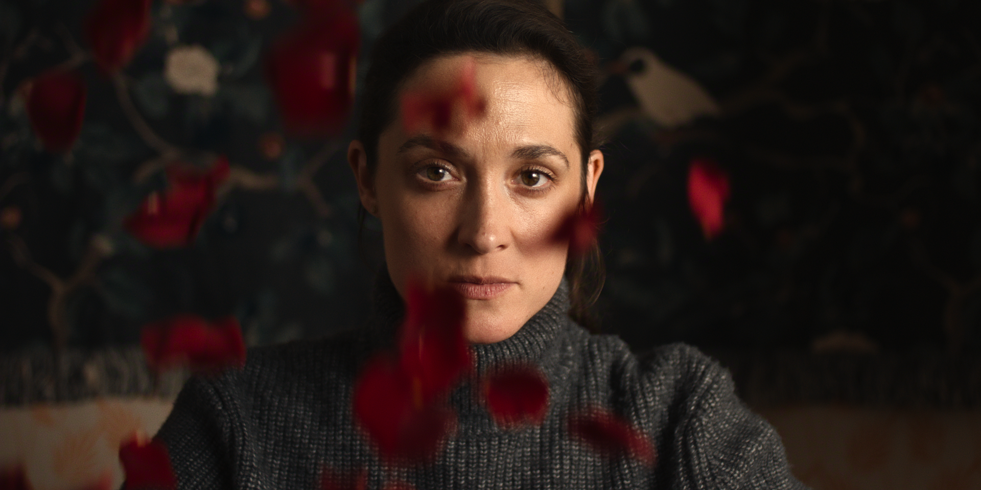 Lisa Konrad looks ahead through out-of-focus red flowers.