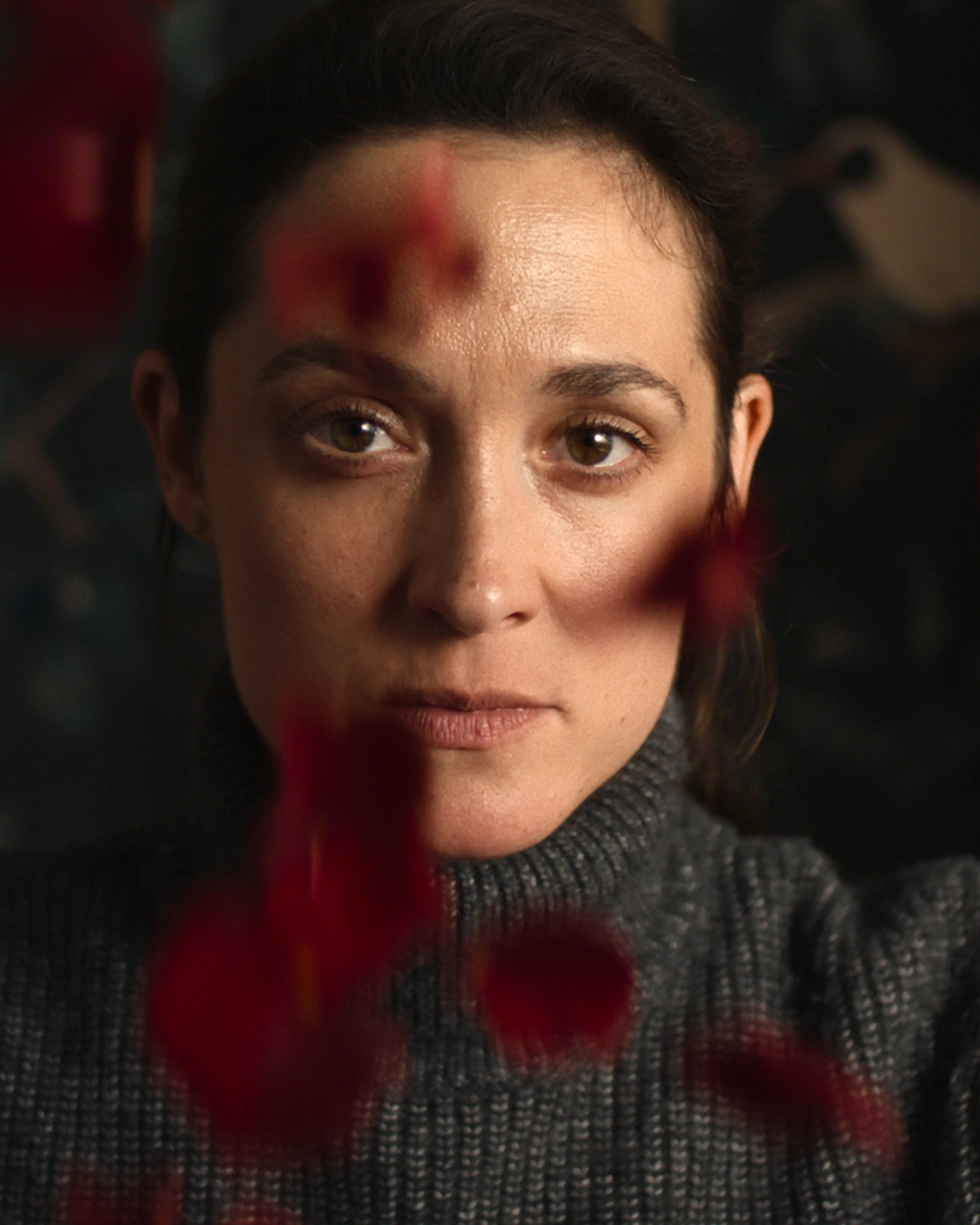 Lisa Konrad looks ahead through out-of-focus red flowers.