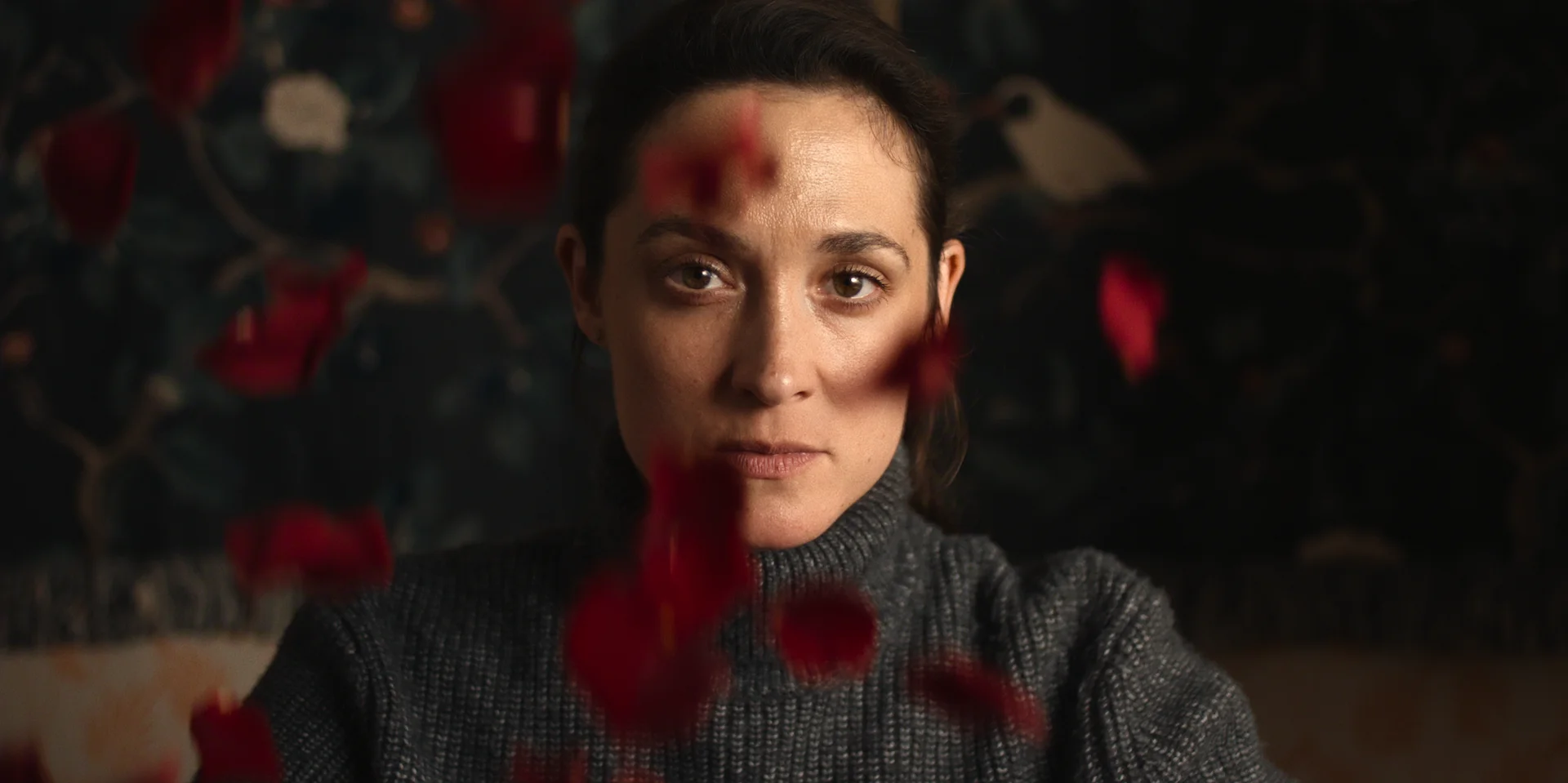 Lisa Konrad looks ahead through out-of-focus red flowers.