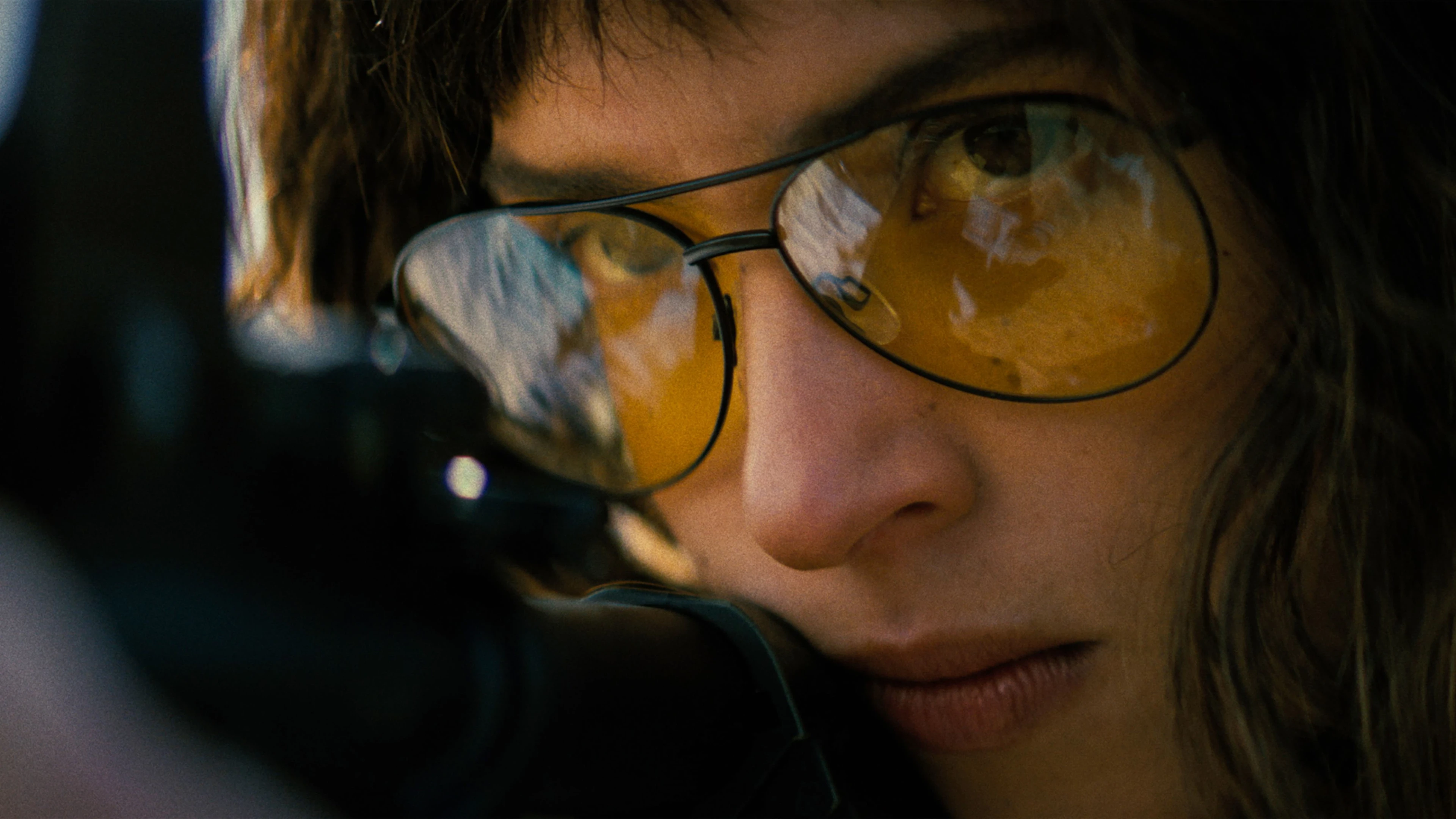 Adria Arjona as Celeste wears amber shooting glasses in a close-up from Onslaught.