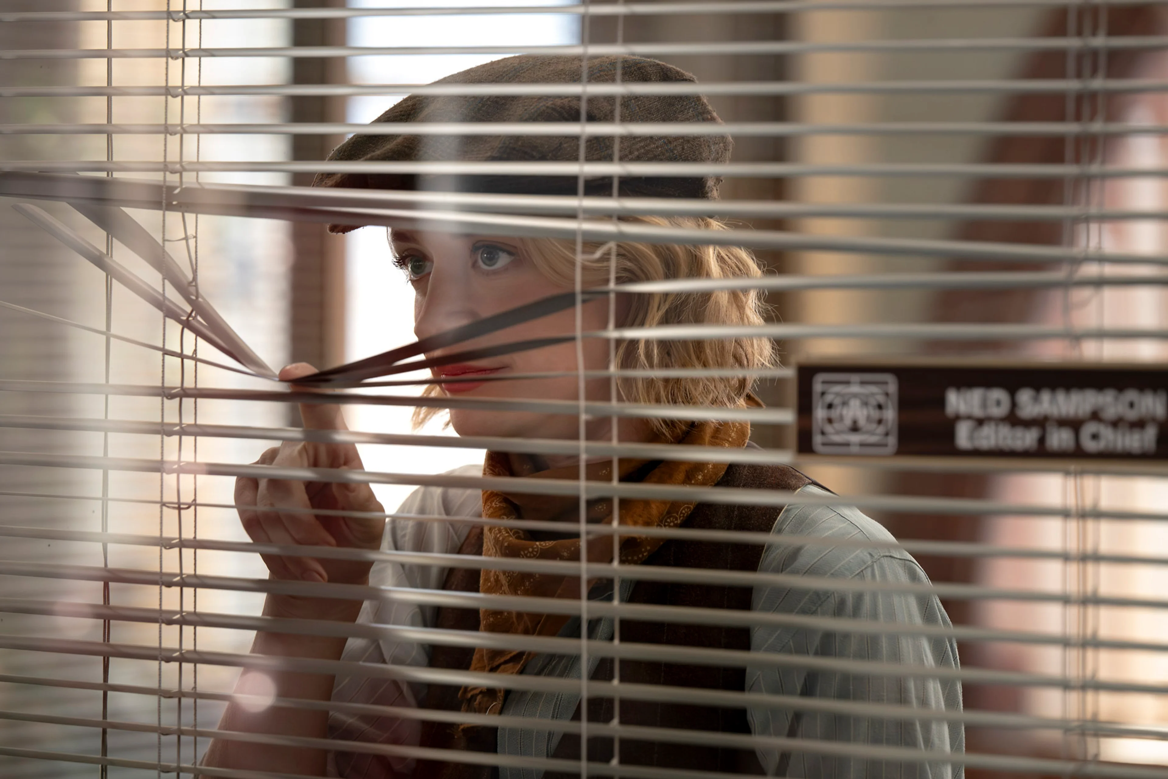 Chelsea Frei as Mare Pritti looks through window blinds in The Paper season two.