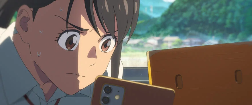 Suzume leans toward her phone beside the small yellow chair.