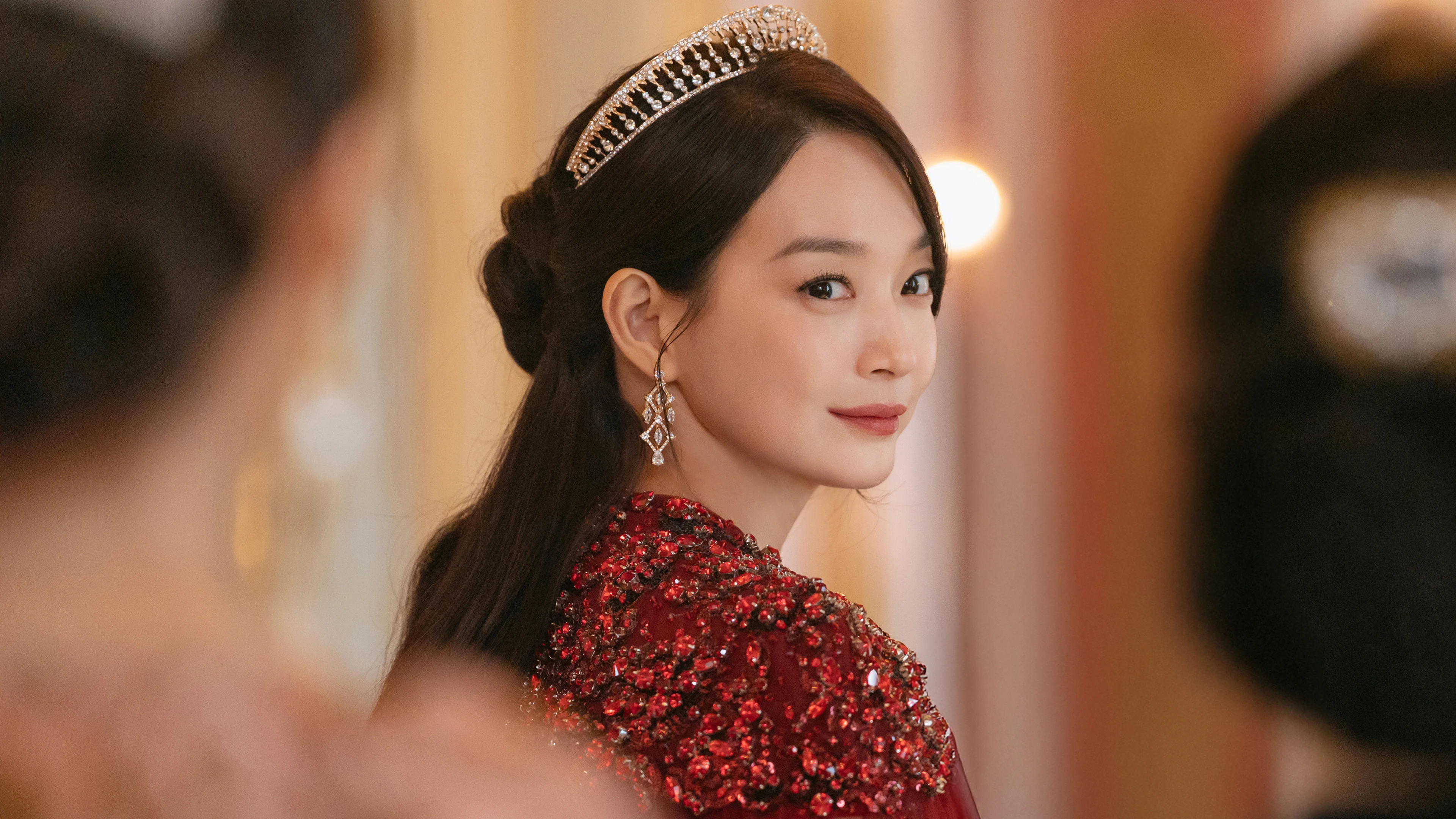 Shin Mina as Empress Navier in a red gown inside the imperial court.