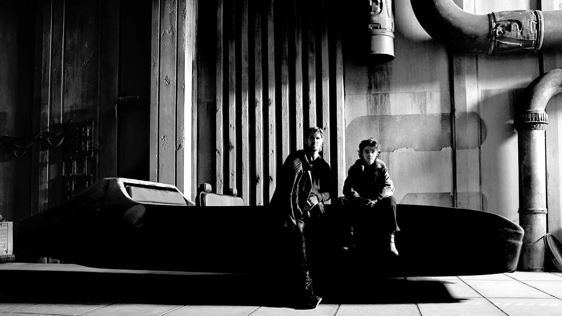 Ryan Gosling and Flynn Gray stand beside a long black vehicle on the Star Wars: Starfighter set.
