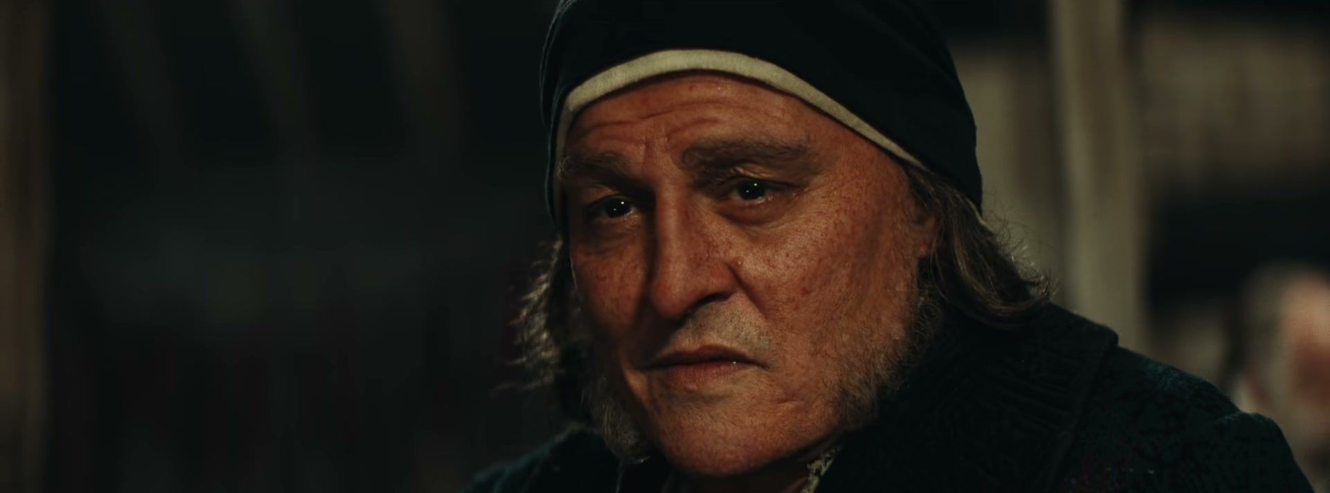 Johnny Depp as Scrooge in a dark cap and coat in Ebenezer.