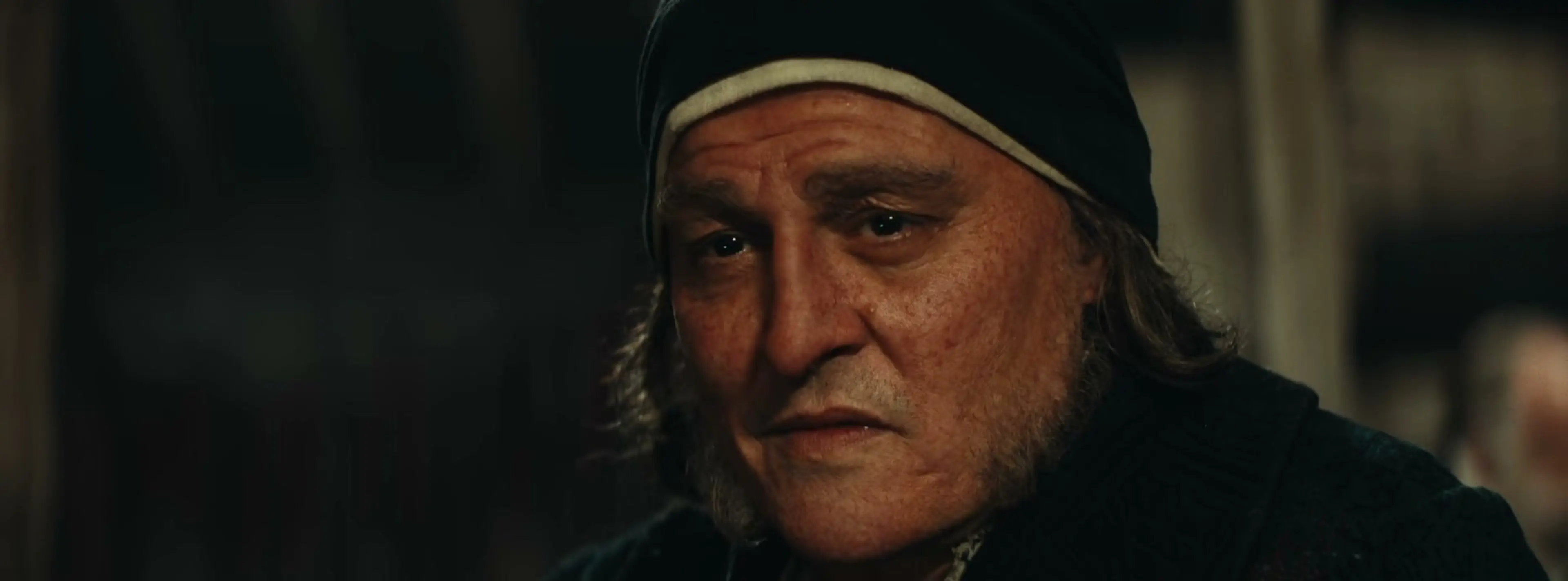 Johnny Depp as Scrooge in a dark cap and coat in Ebenezer.