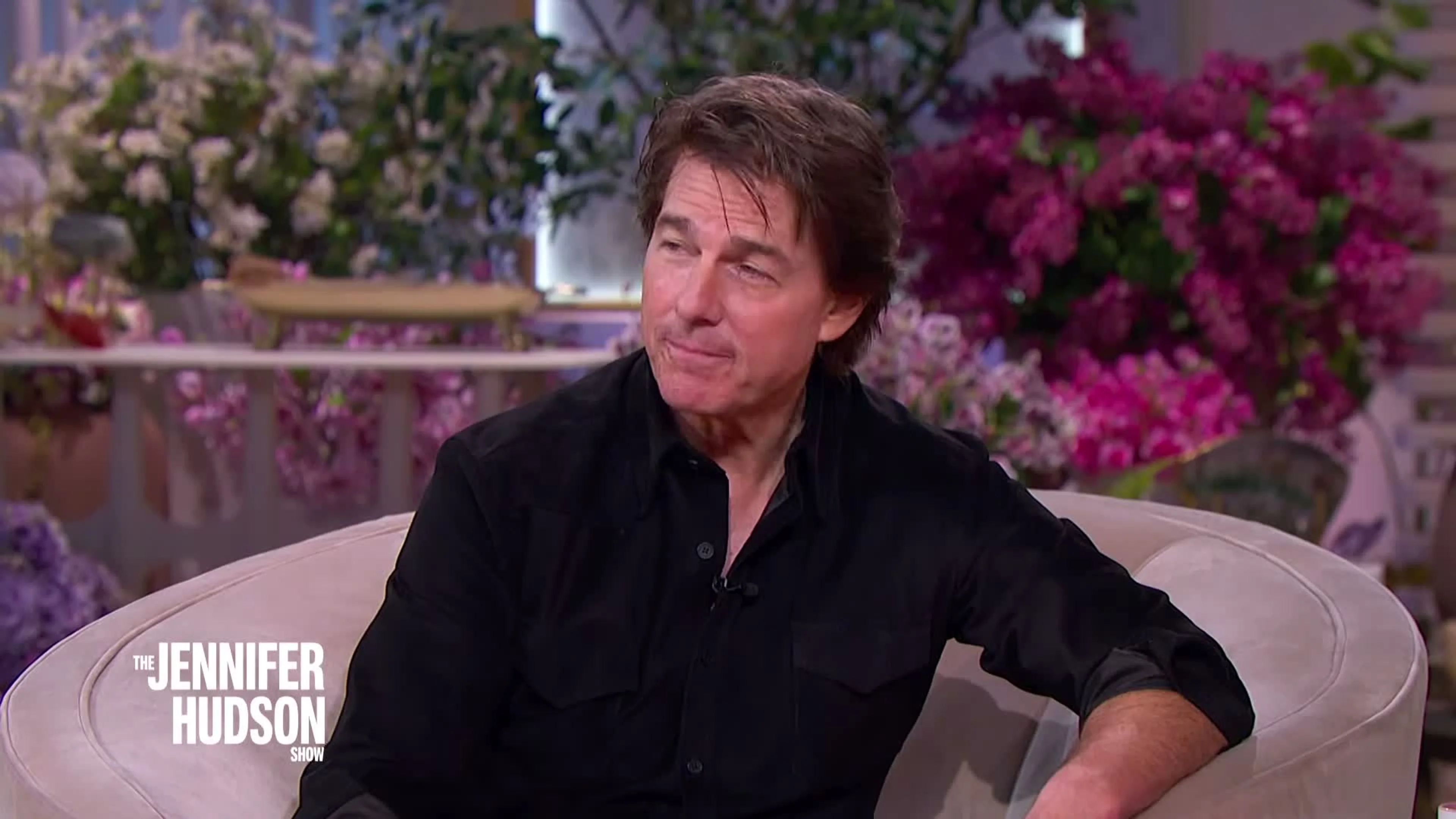 Tom Cruise sits on a pale armchair on The Jennifer Hudson Show set.