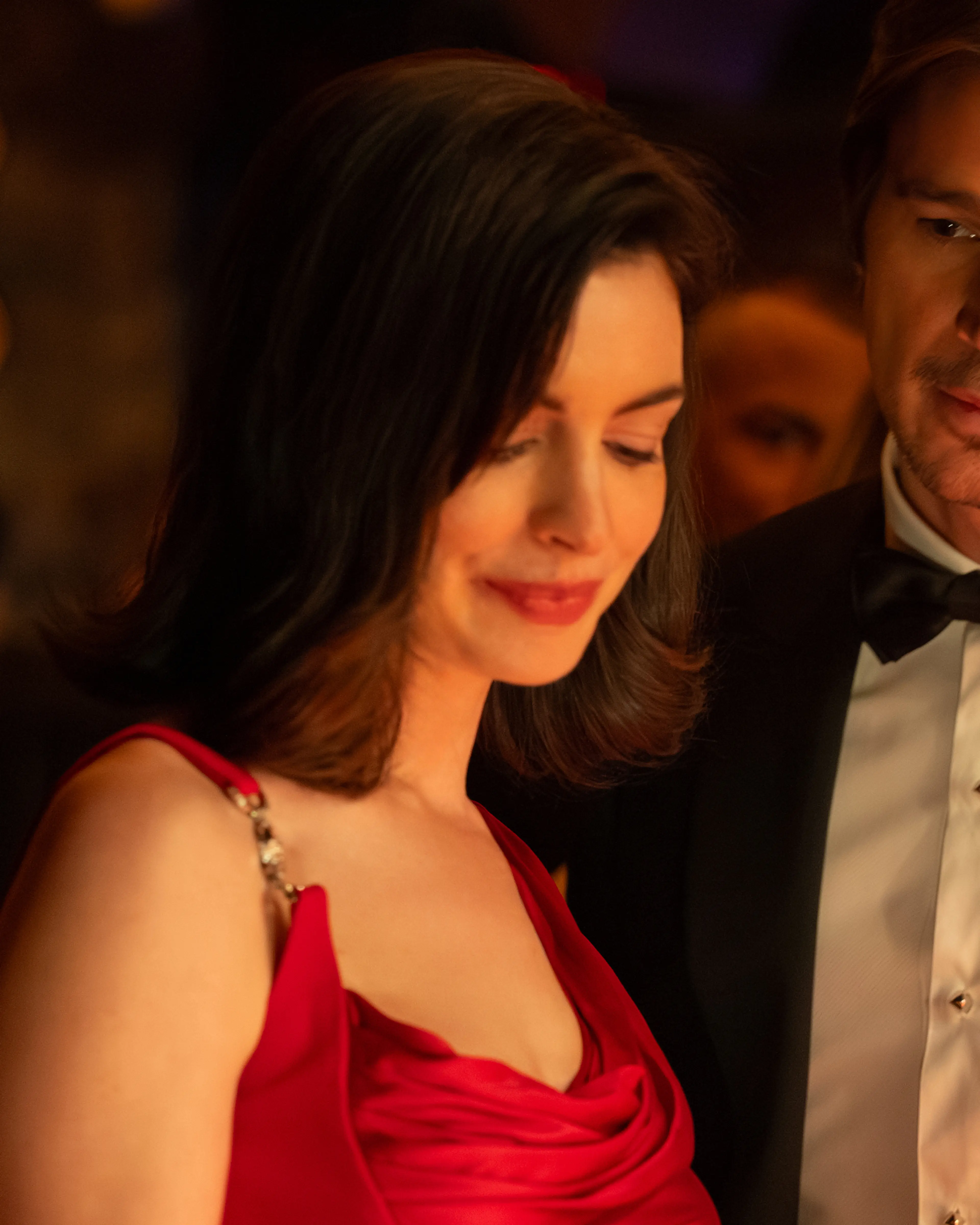 Verity wears a red dress beside Jeremy, who wears a tuxedo at an evening event.