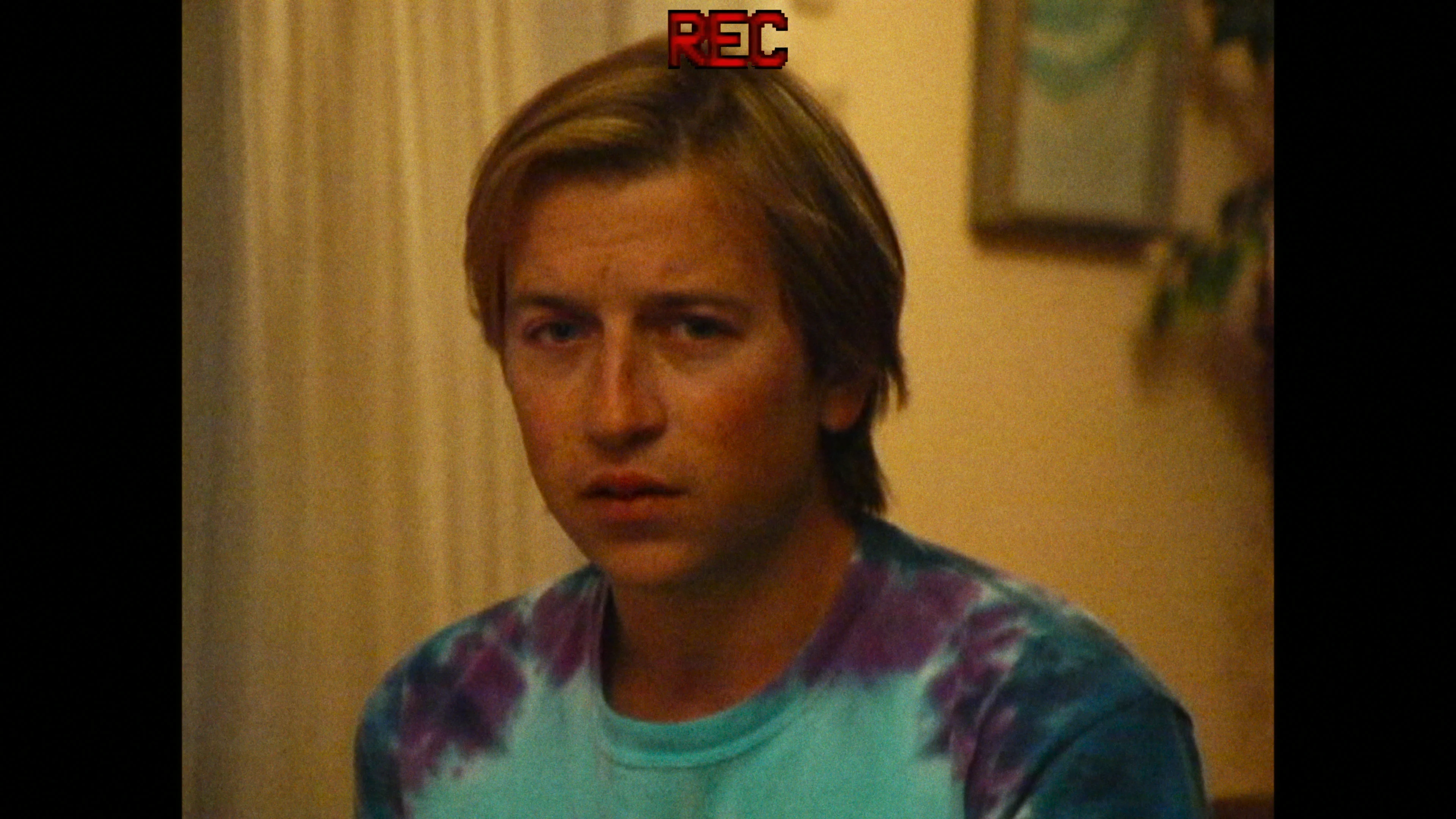 Skyler Gisondo as Dan wears a tie-dye shirt in an image marked REC.