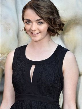 Portrait of Maisie Williams smiling in a black sleeveless dress.