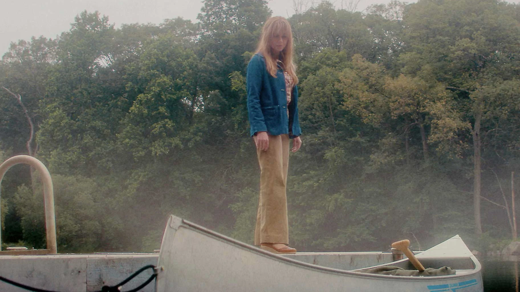 Linda Cardellini as Pamela Voorhees stands beside a rowboat on a foggy lake.
