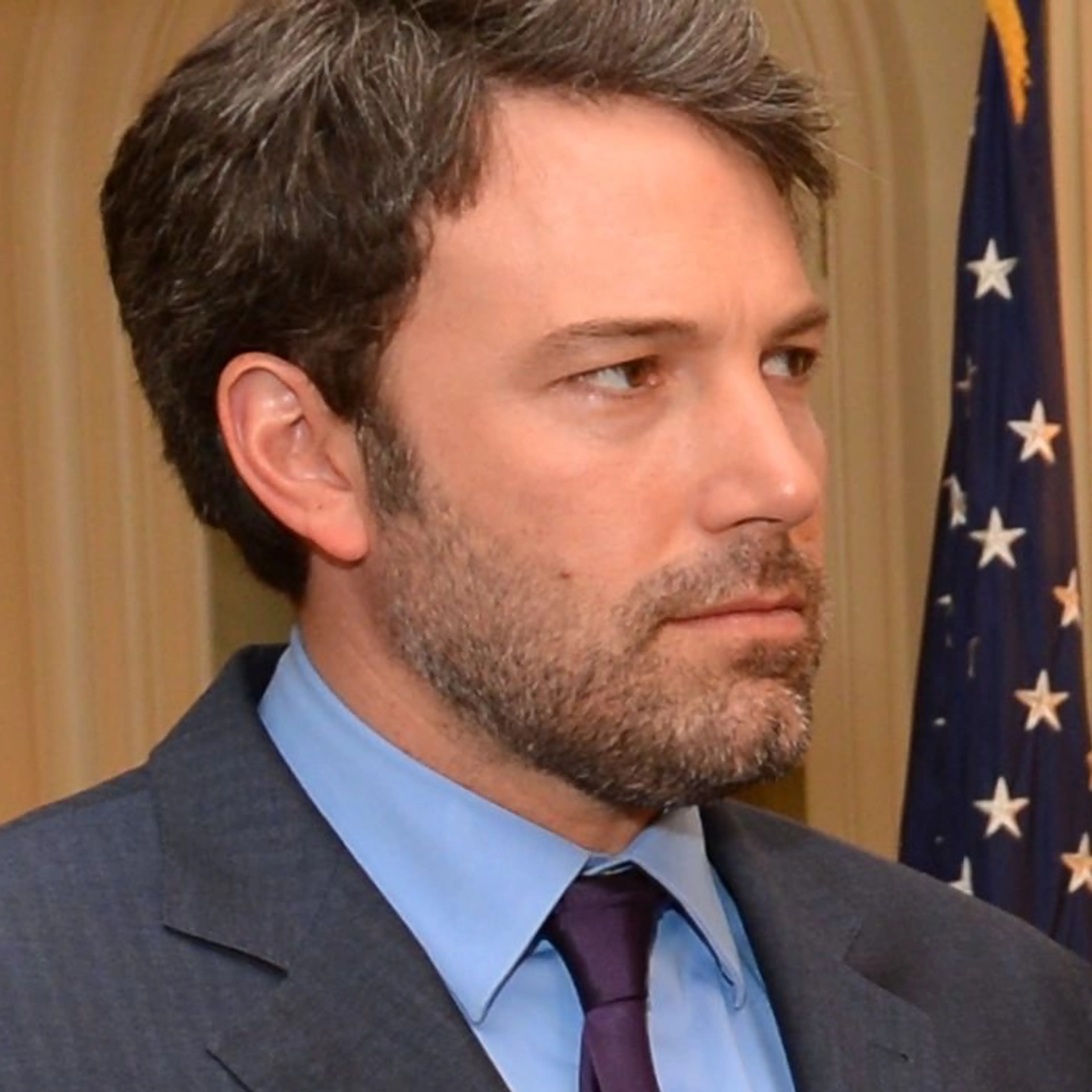 Ben Affleck in a dark suit and purple tie during a 2014 State Department meeting.