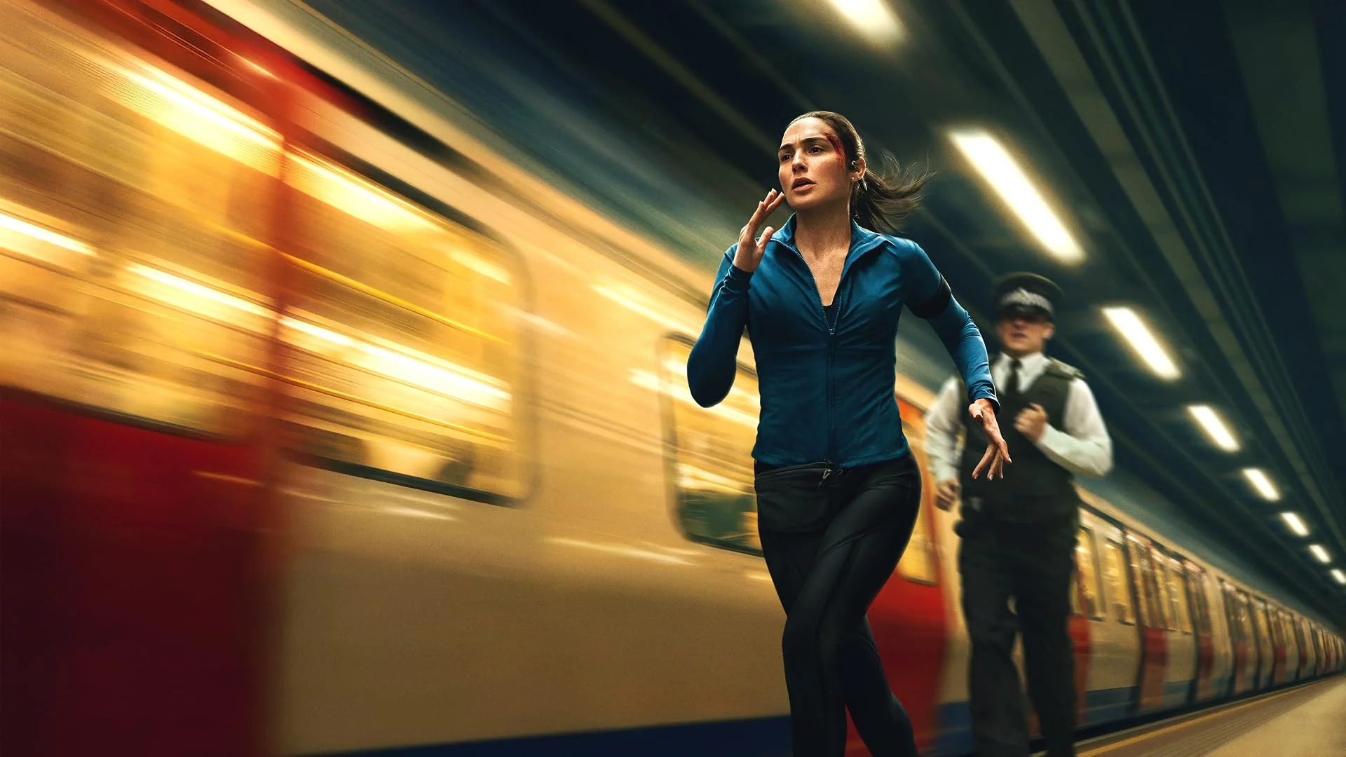 Gal Gadot as Maia Marten runs beside a moving Underground train while a police officer follows in The Runner.