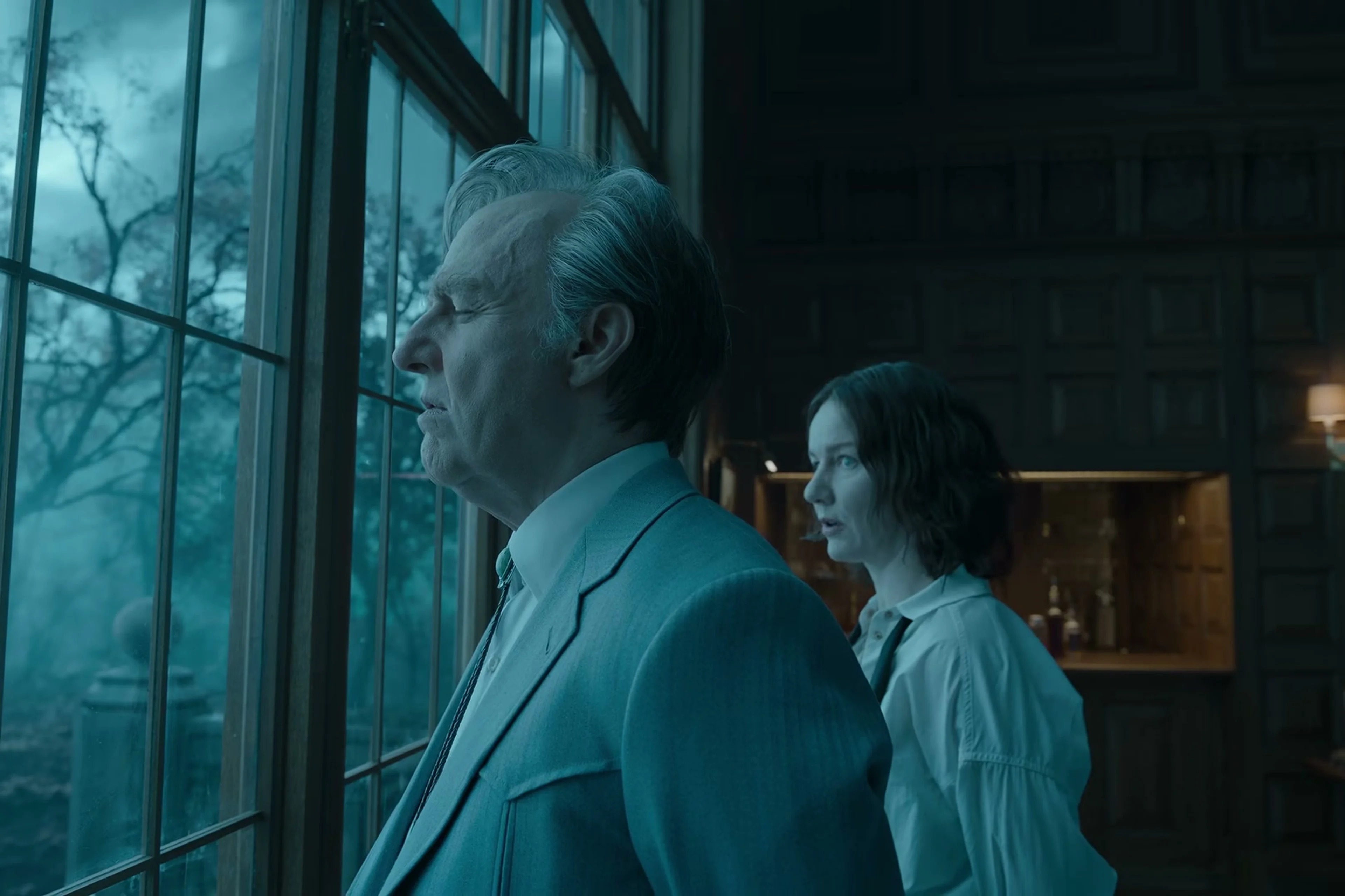 Tom Cruise as Digger Rockwell stands beside a woman at a window in Digger.