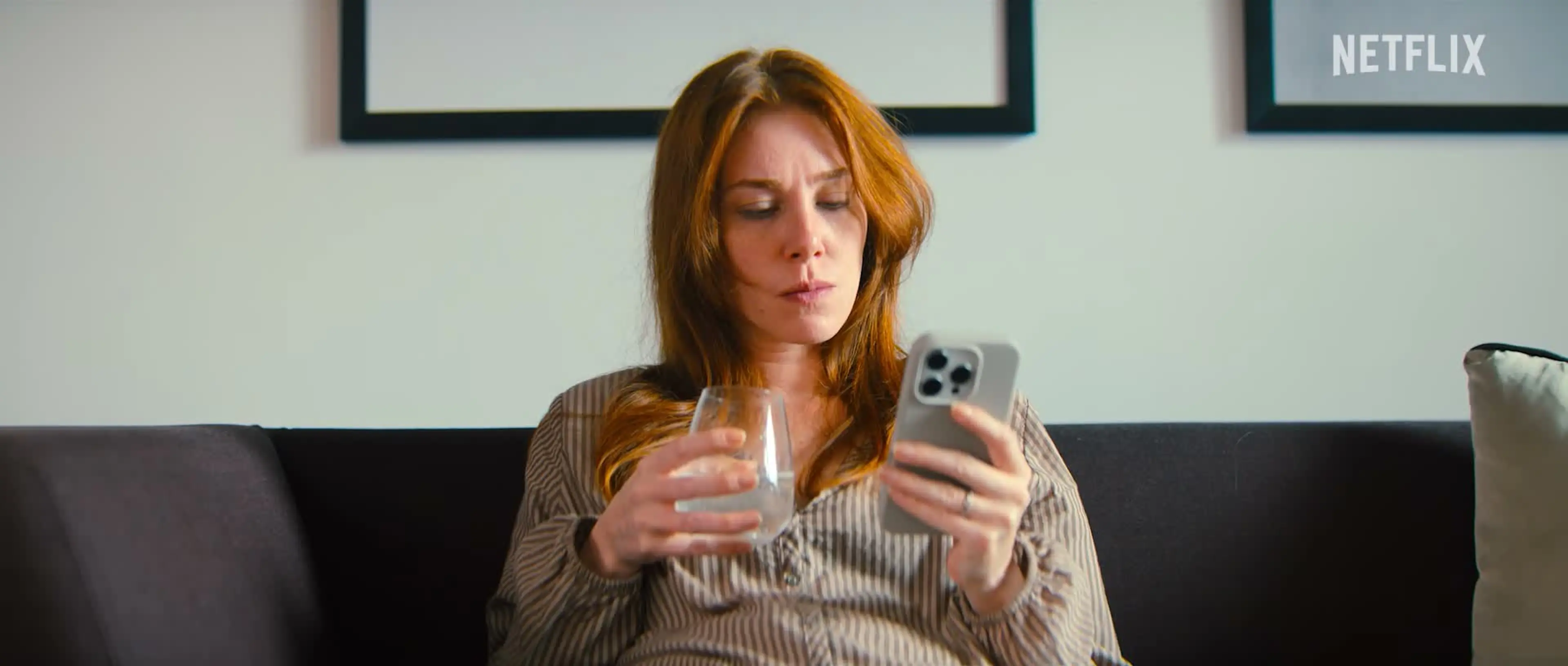 Funda sits on a sofa checking her phone in the Netflix series Not a Stranger.