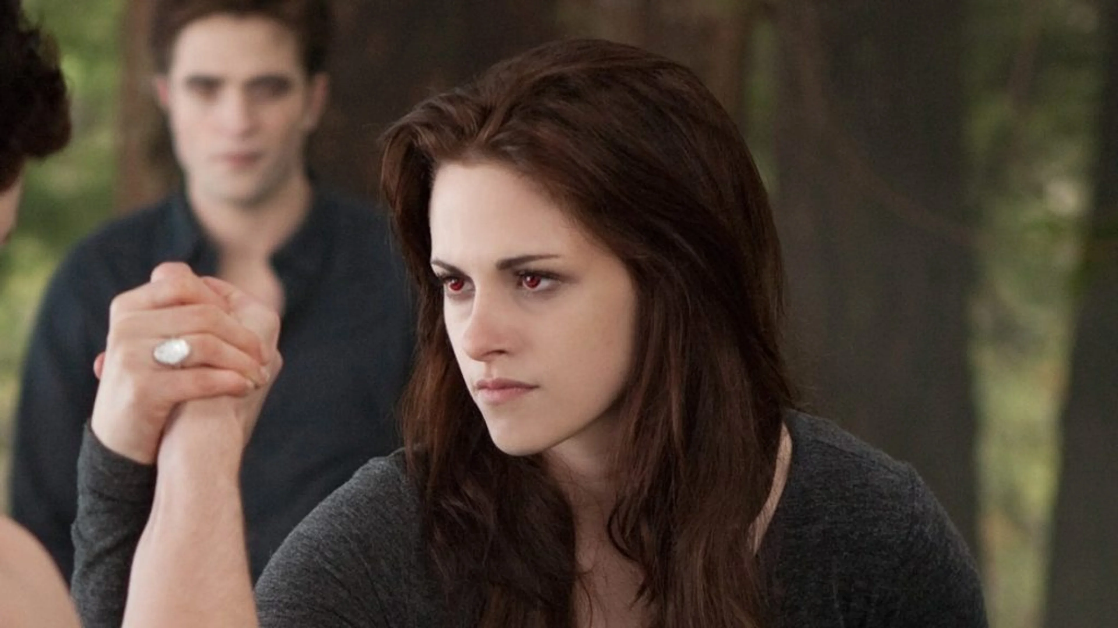 Bella Swan holds another person’s hand with Edward behind her in Breaking Dawn – Part 2.