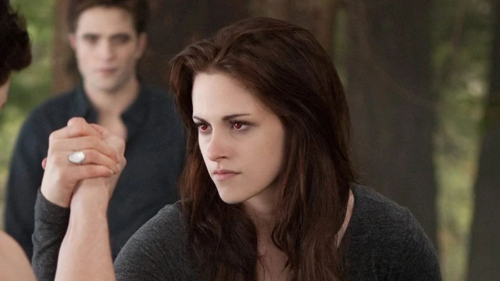 Bella Swan holds another person’s hand with Edward behind her in Breaking Dawn – Part 2.