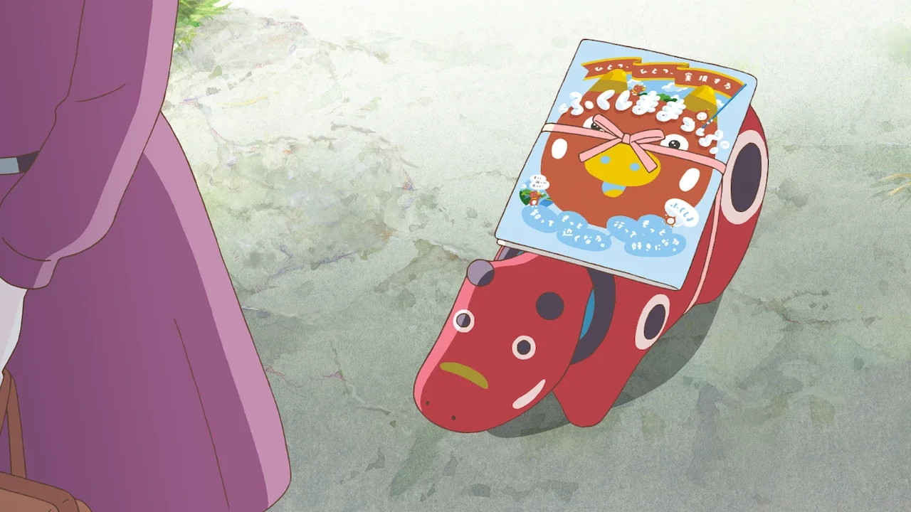 Sophie sees a red akabeko figure beside a Fukushima travel display.