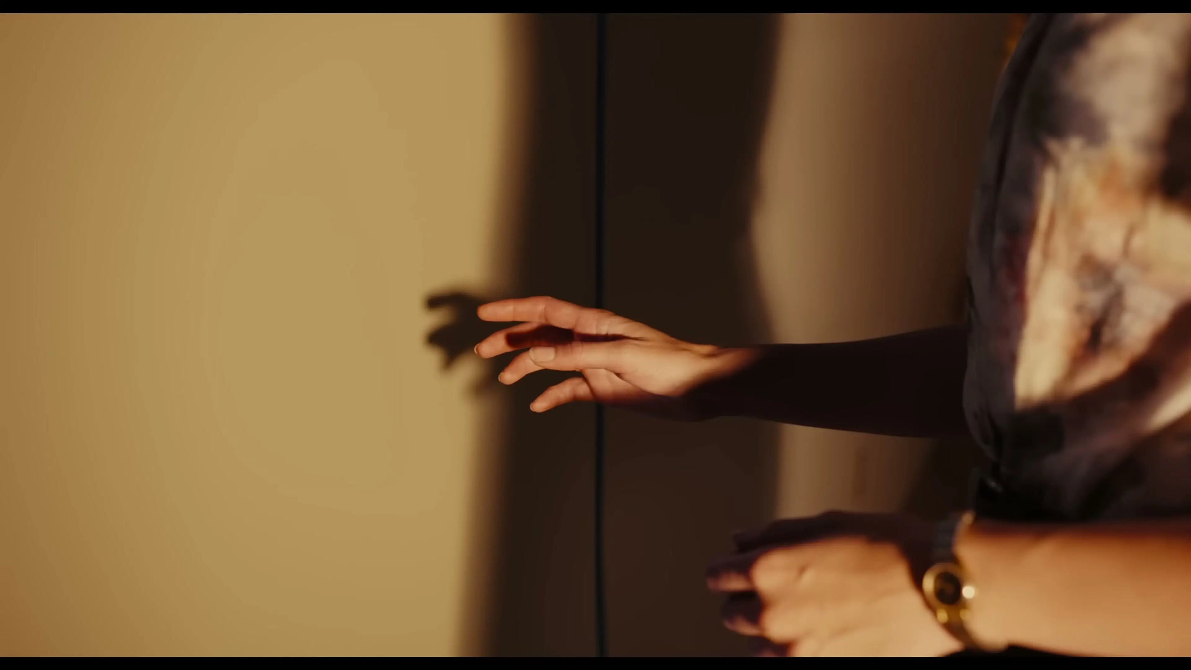 A woman reaches toward a narrow opening in a wall.