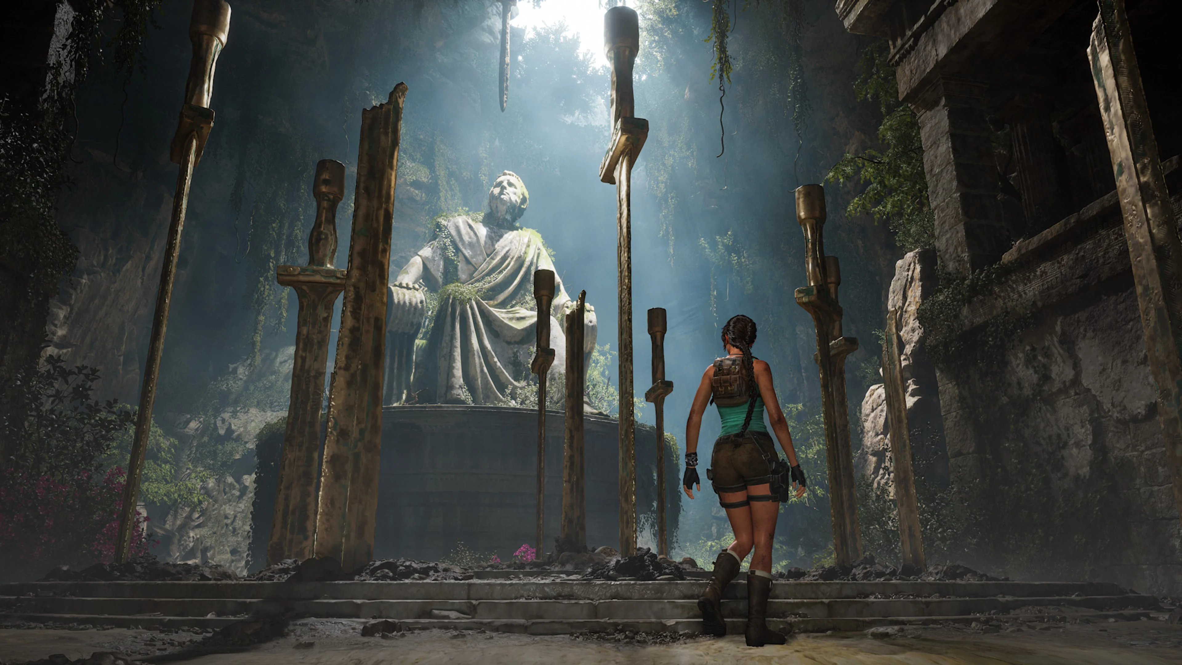 Lara Croft walks between towering swords toward a seated stone statue inside a Greek tomb.