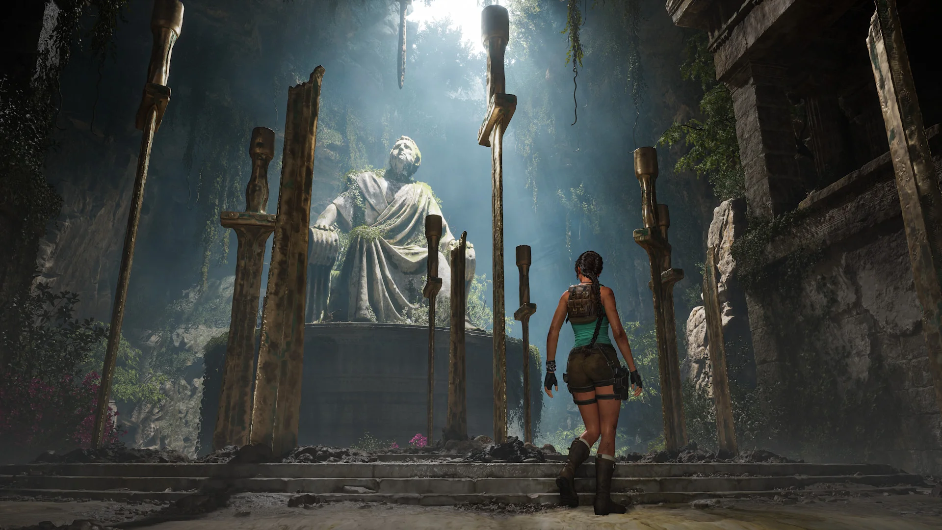 Lara Croft walks between towering swords toward a seated stone statue inside a Greek tomb.