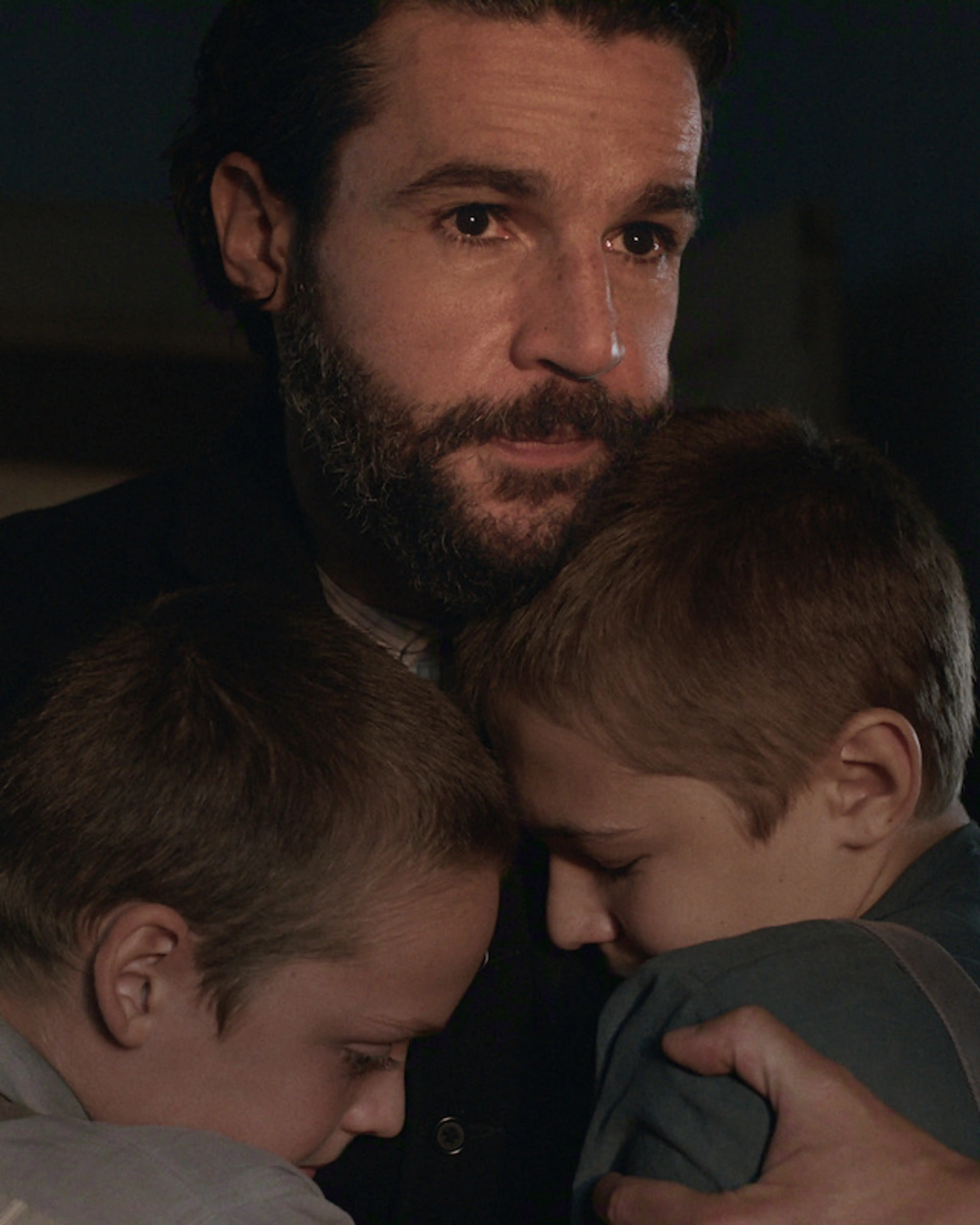 Christopher Abbott as Adam Trask holds two boys in East of Eden.