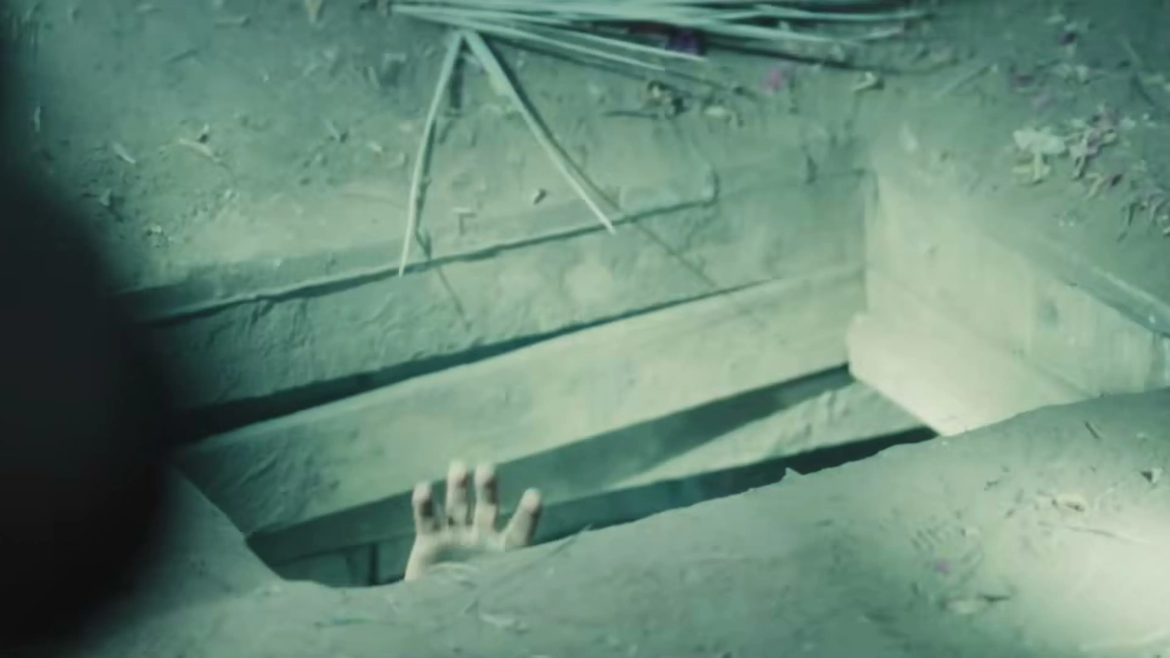 A man looks down into a narrow hiding place in a dramatized High Value Target scene.