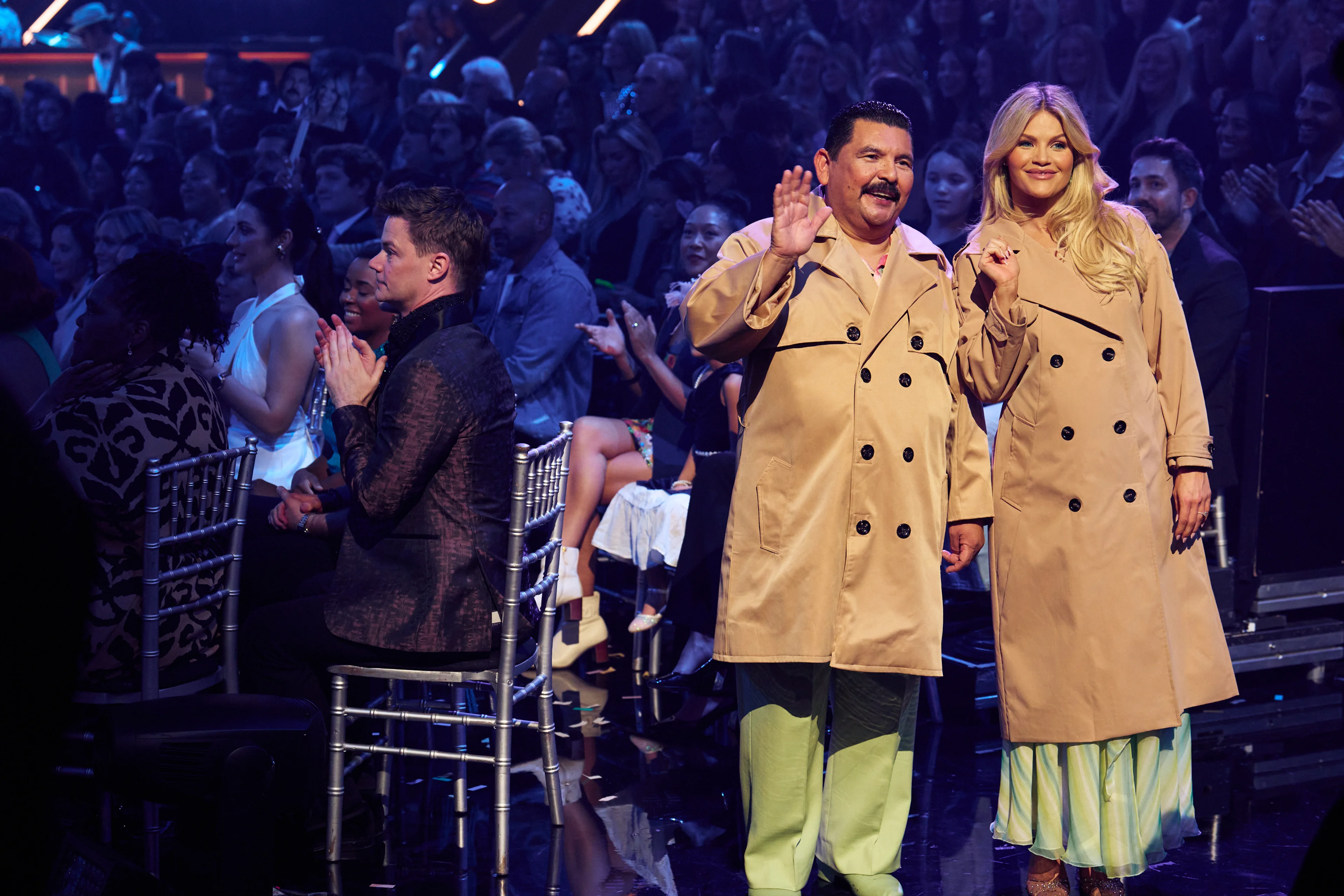 Guillermo Rodriguez and Witney Carson wave to the audience in matching coats at Dancing with the Stars.