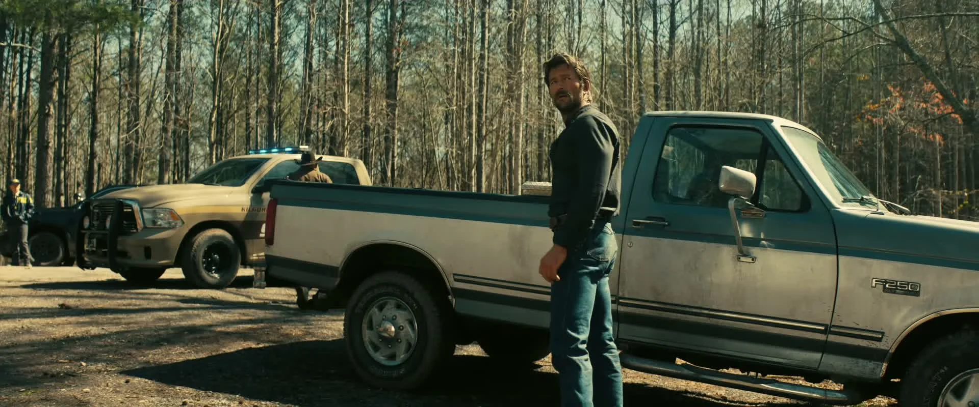 The cowboy stands beside a pickup truck during the search.