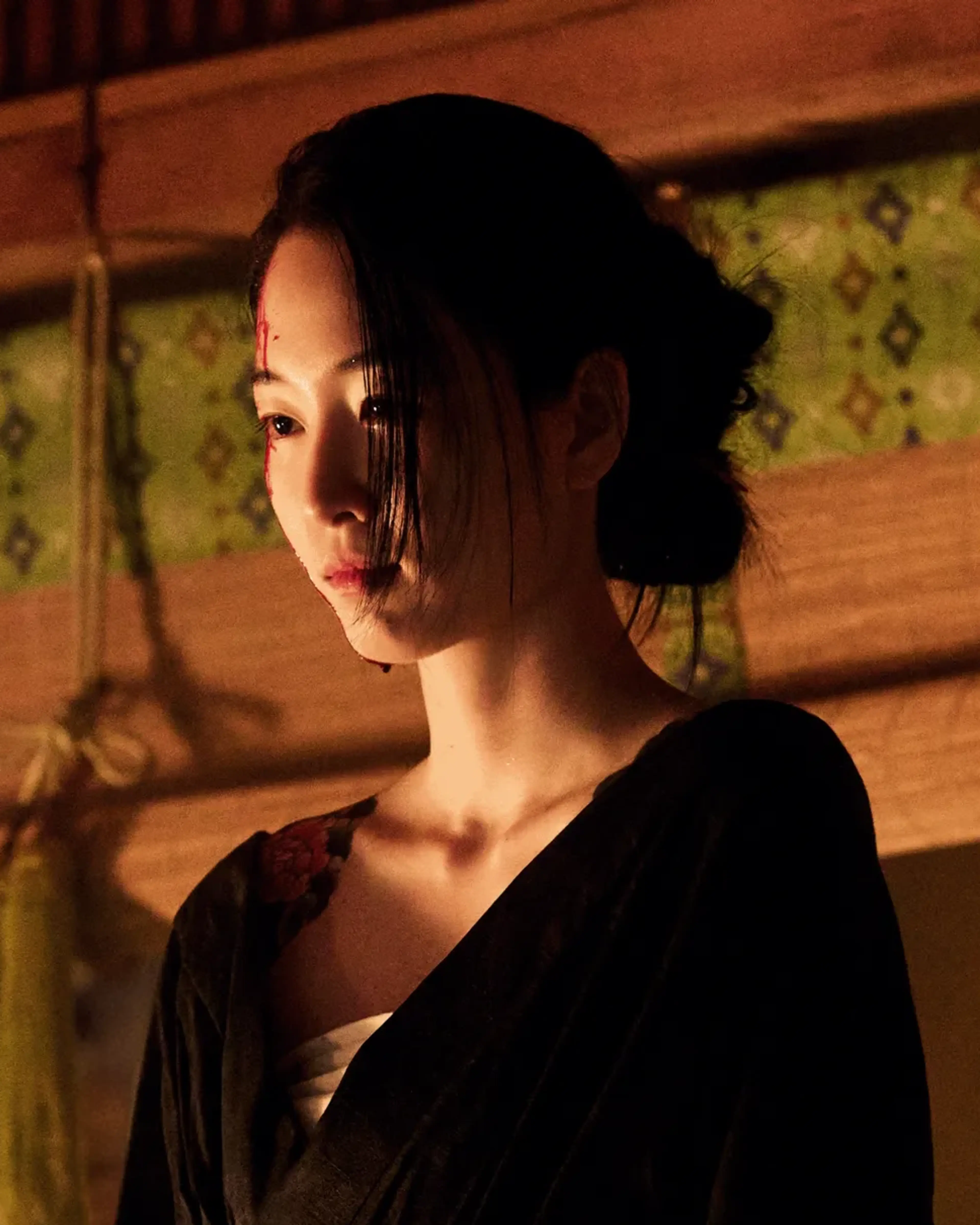 Won Ji-an as Yuji wears a dark robe in a warmly lit wood-paneled room.