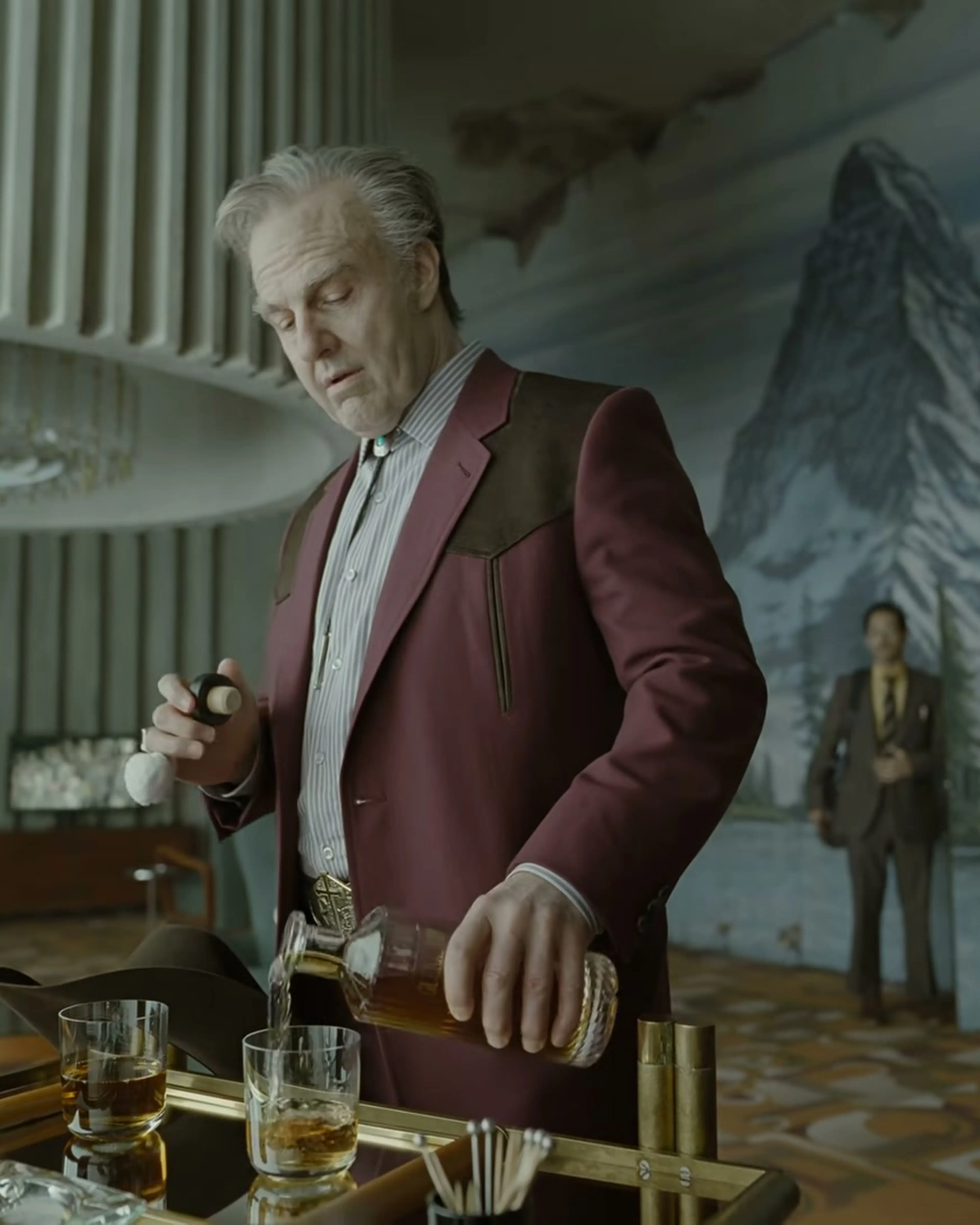Tom Cruise as Digger Rockwell pours a drink in a room with a mountain mural.
