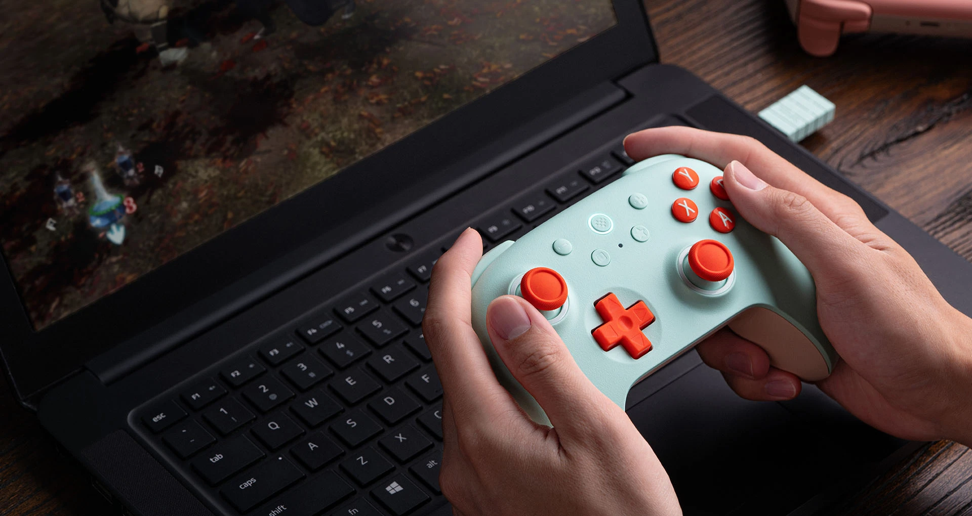 Mint Ultimate 2C Wireless with coral buttons held beside a laptop