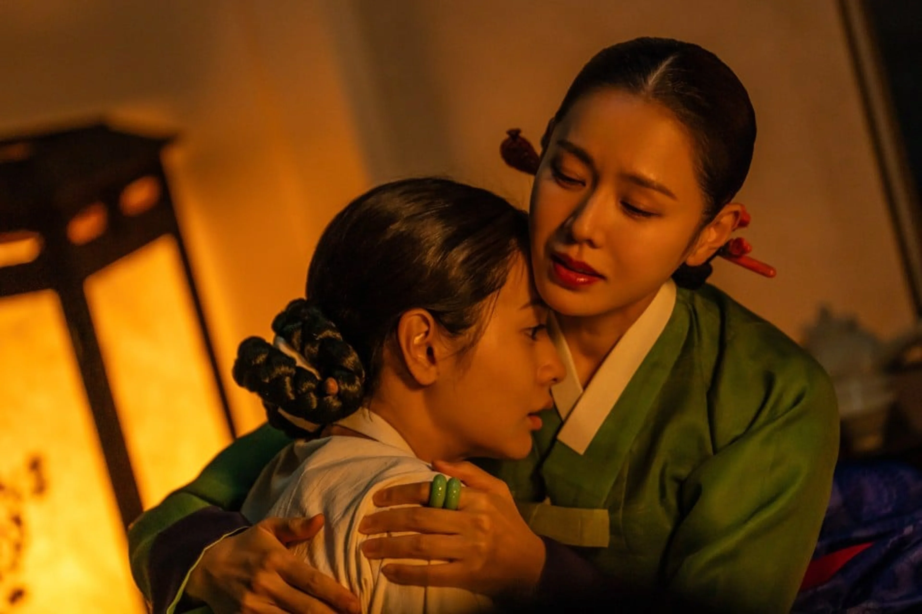 Lady Cho holds Hui-yeon close in a warmly lit room.