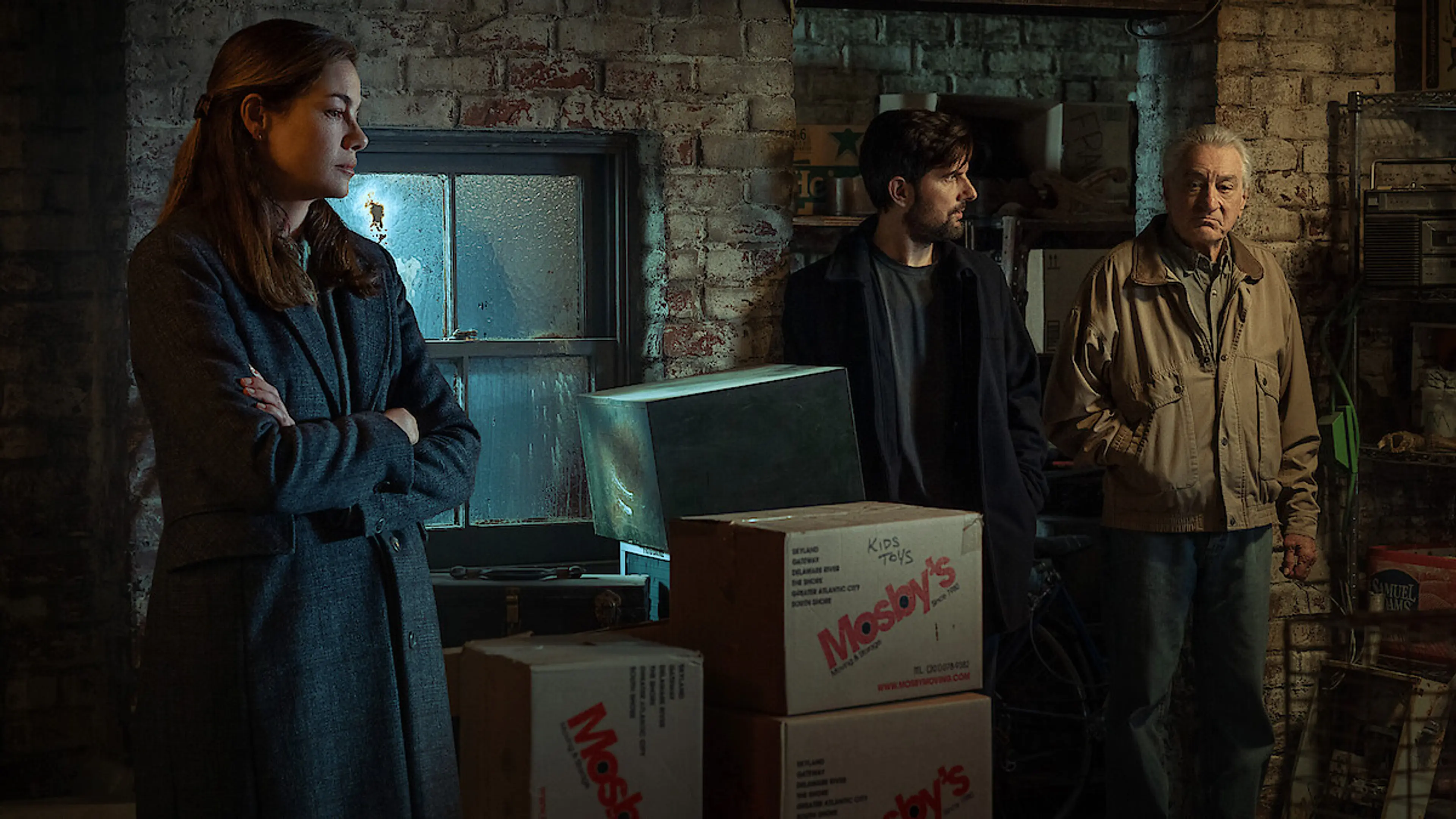 Amanda Beck, Tom Kennedy, and Pete Willis stand among boxes in a basement in The Whisper Man.