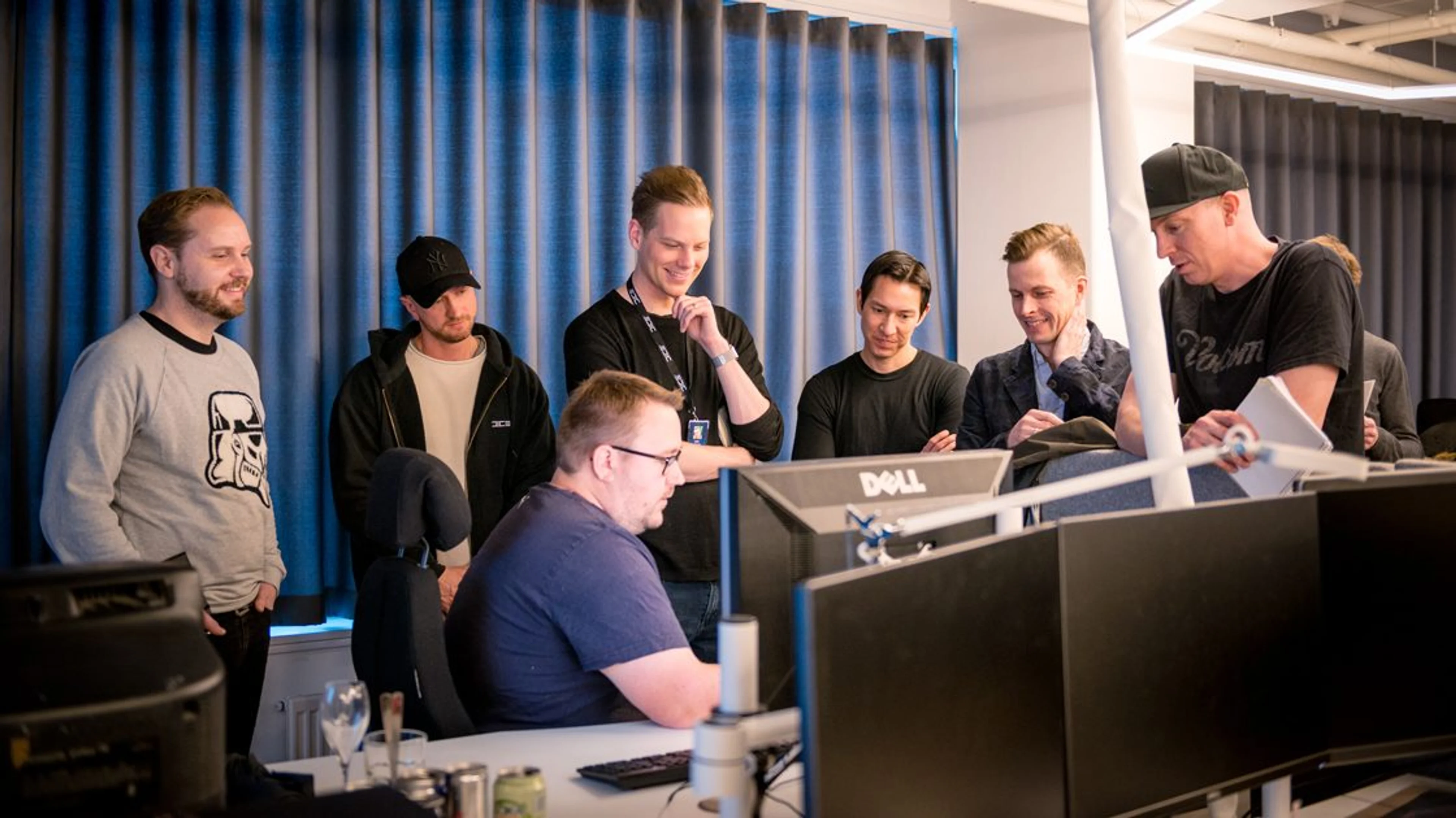 Electronic Arts studio leads gather around a workstation in an official EA photo.