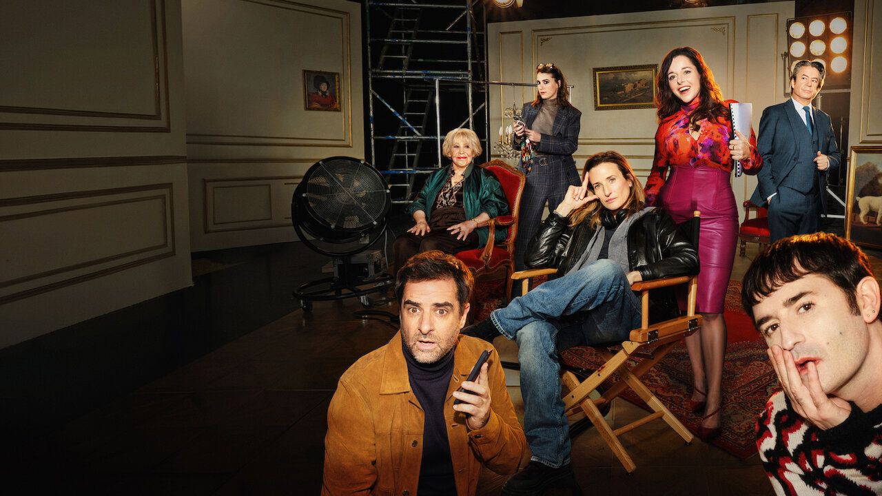 The Call My Agent! ensemble poses on a film set, with Camille Cottin seated at center.