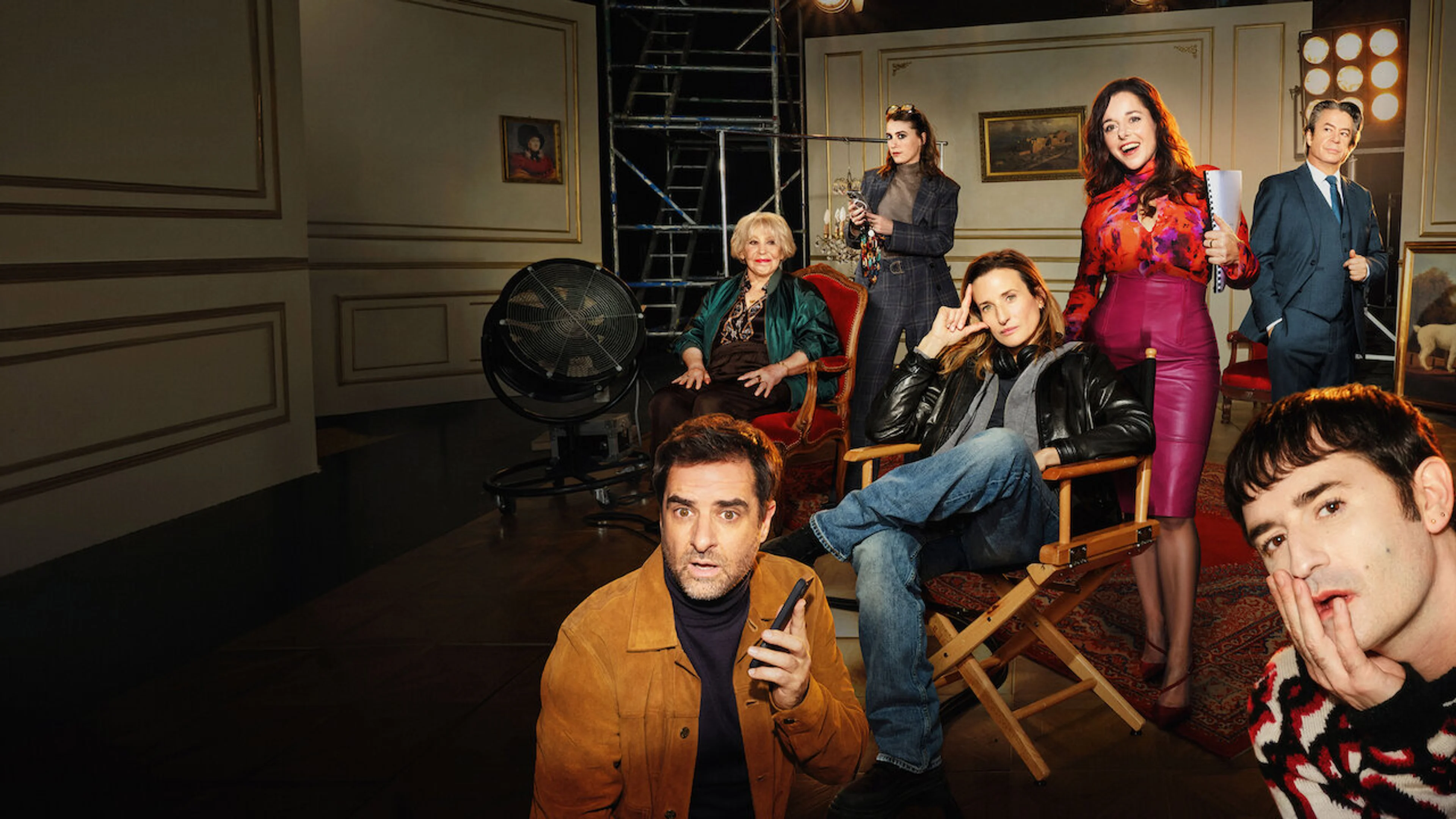 The Call My Agent! ensemble poses on a film set, with Camille Cottin seated at center.