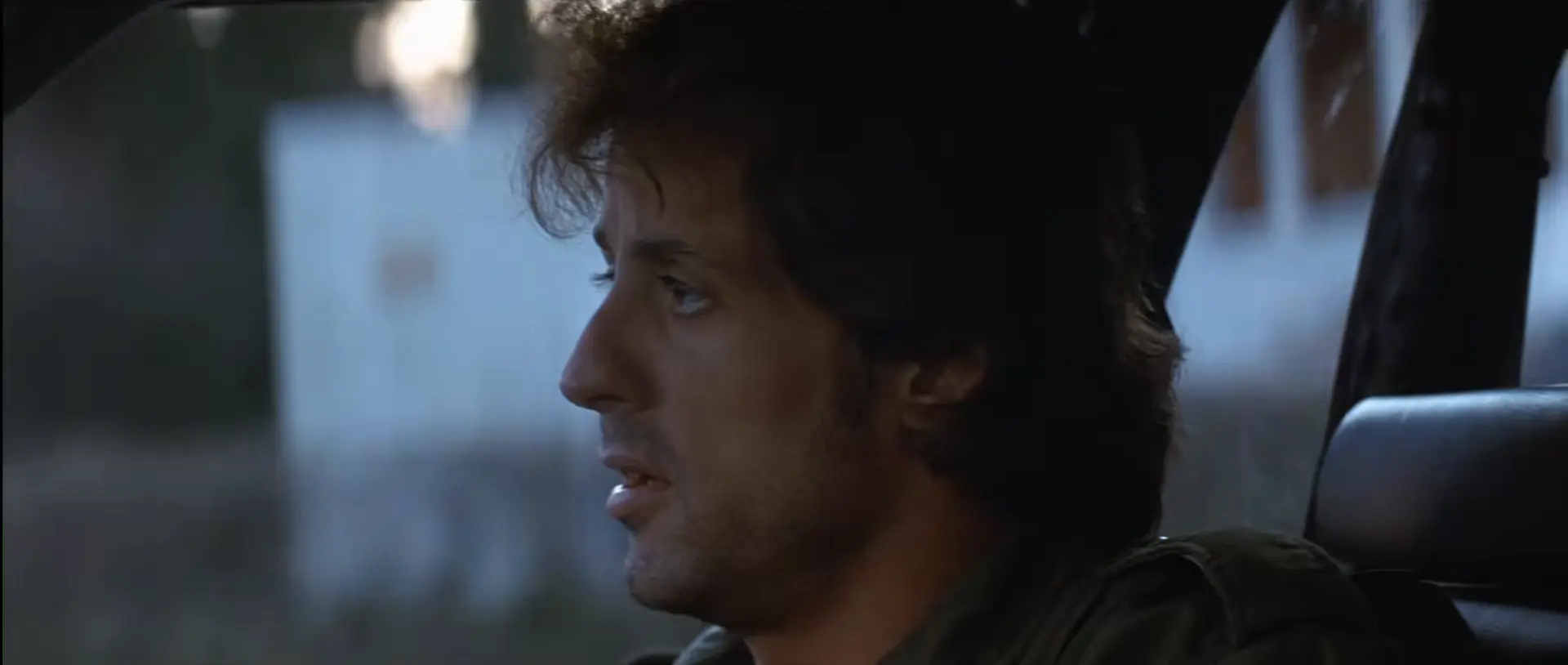 Sylvester Stallone as John Rambo looks out from the passenger seat of a vehicle.