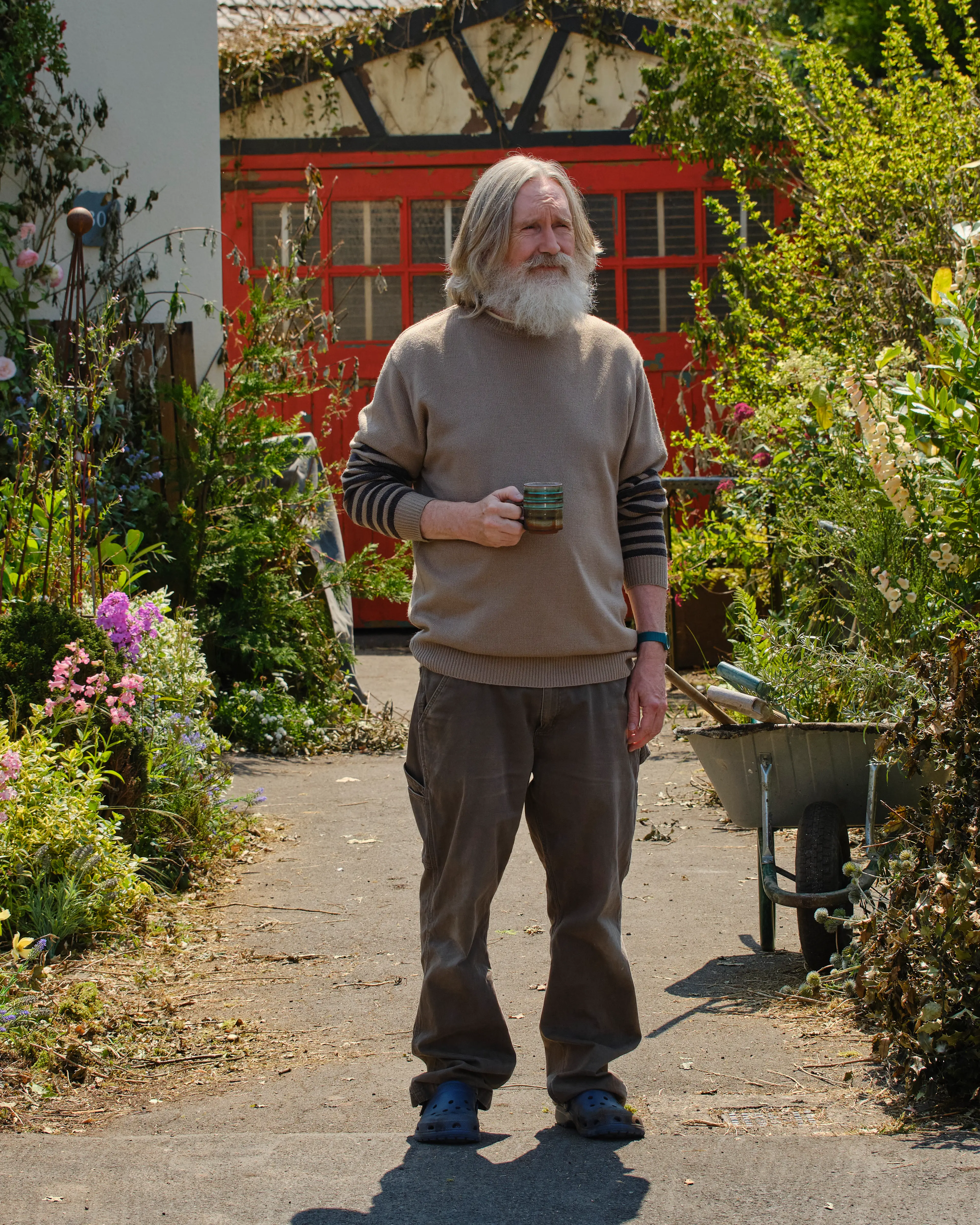 Michael Sleep stands in a garden holding a mug.
