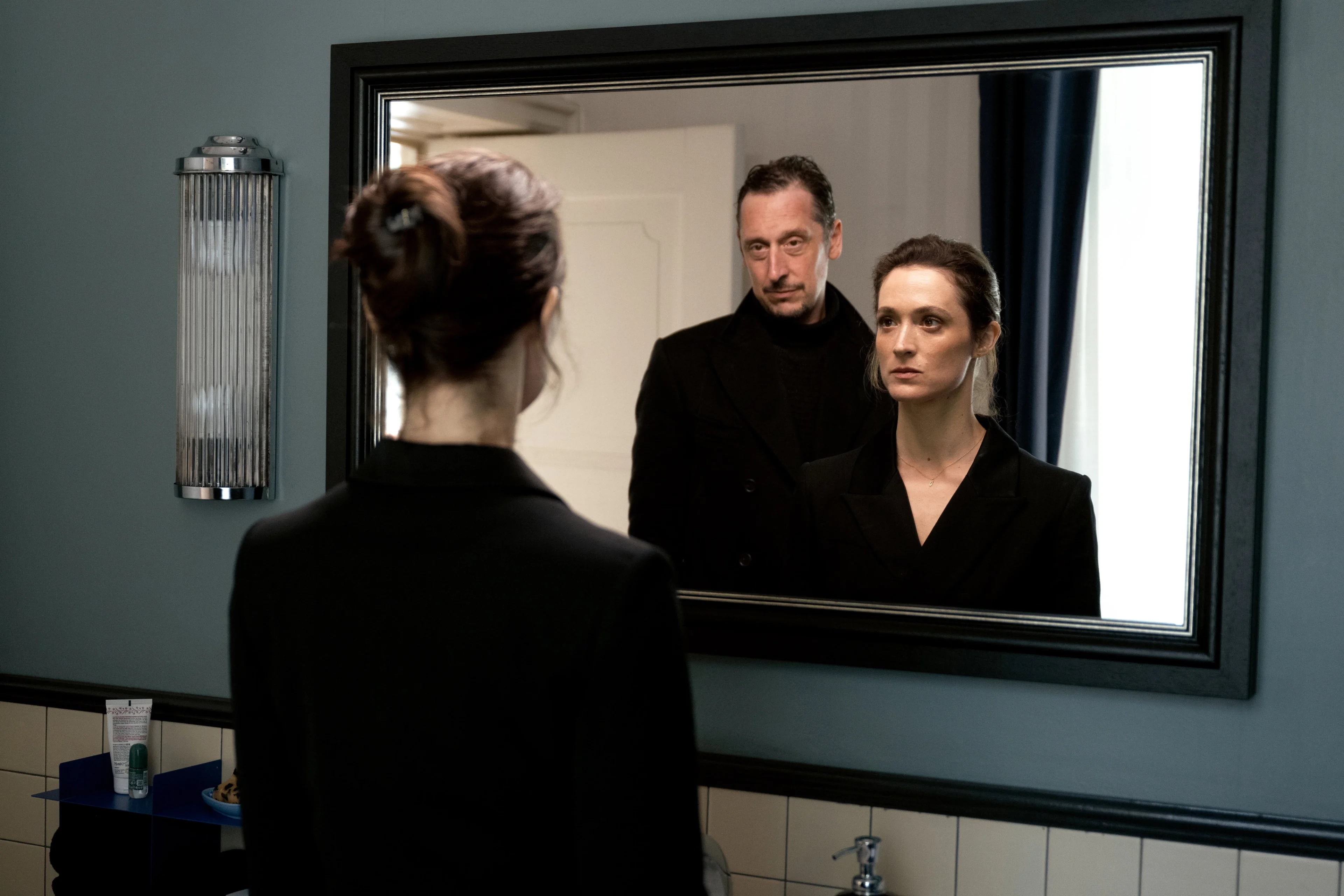 Lisa Konrad and Robert Lenzen appear together in a mirror, with Lisa also seen from behind.
