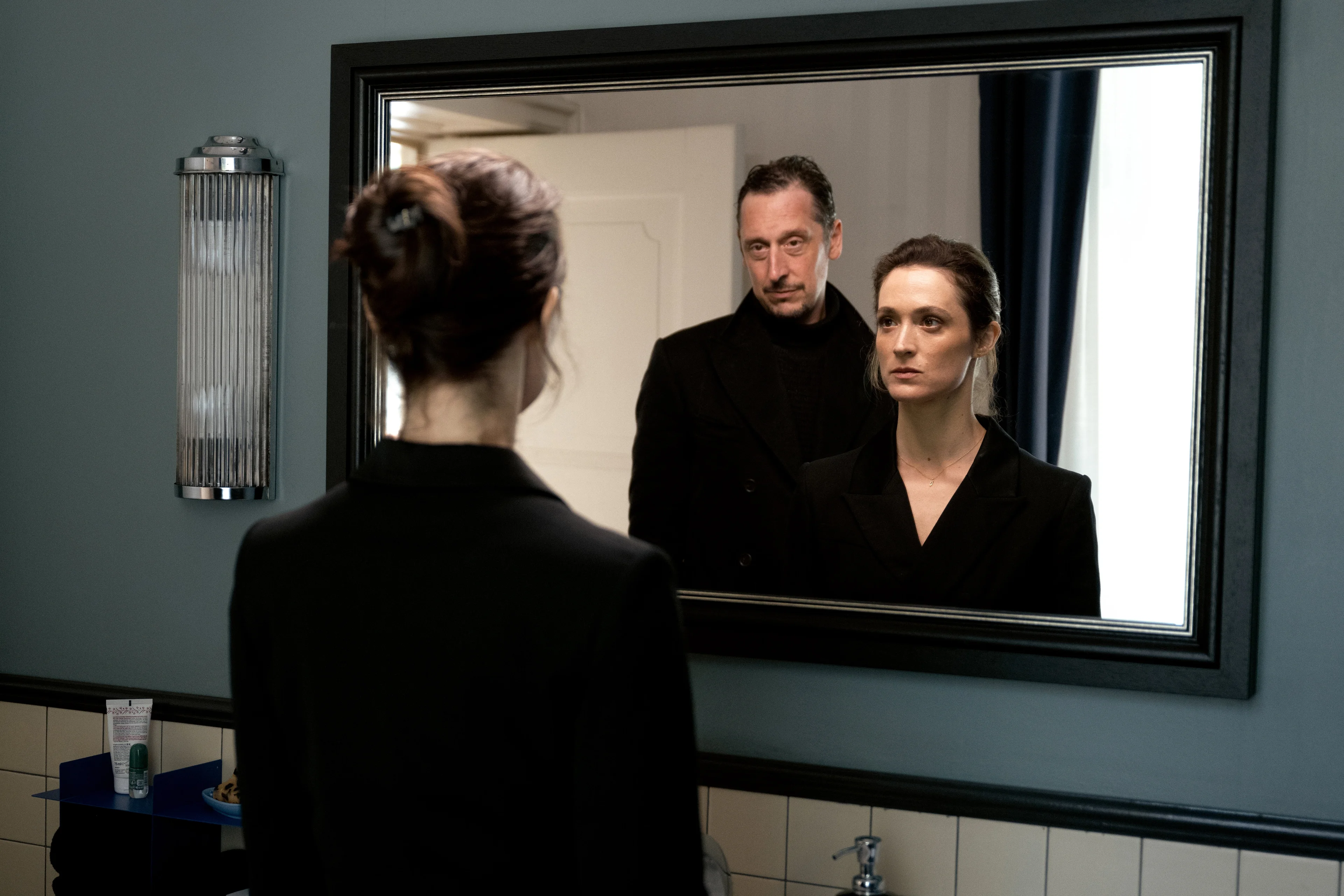 Lisa Konrad and Robert Lenzen appear together in a mirror, with Lisa also seen from behind.