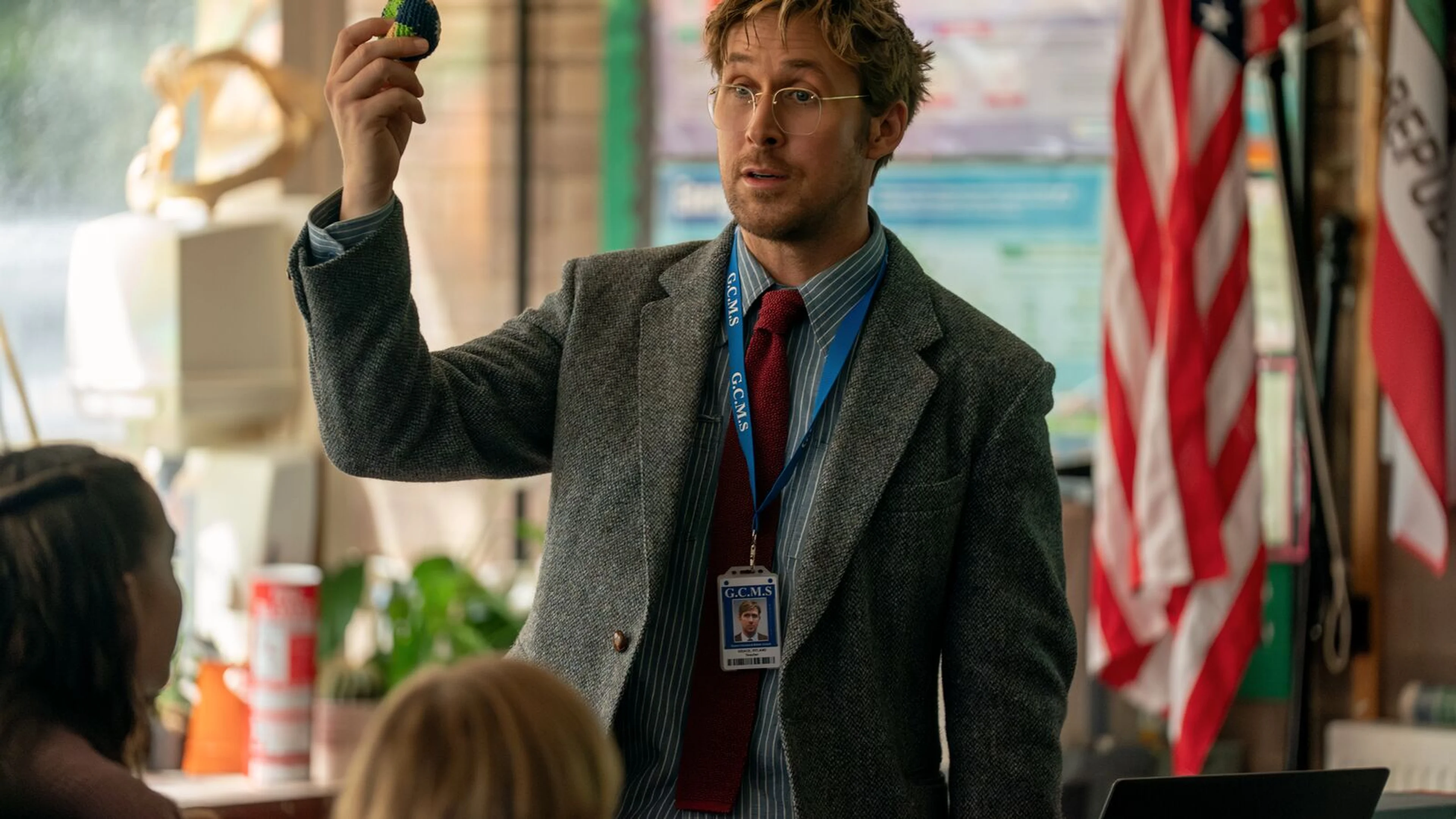 Ryland Grace holds up a small knitted ball while teaching a classroom of students.