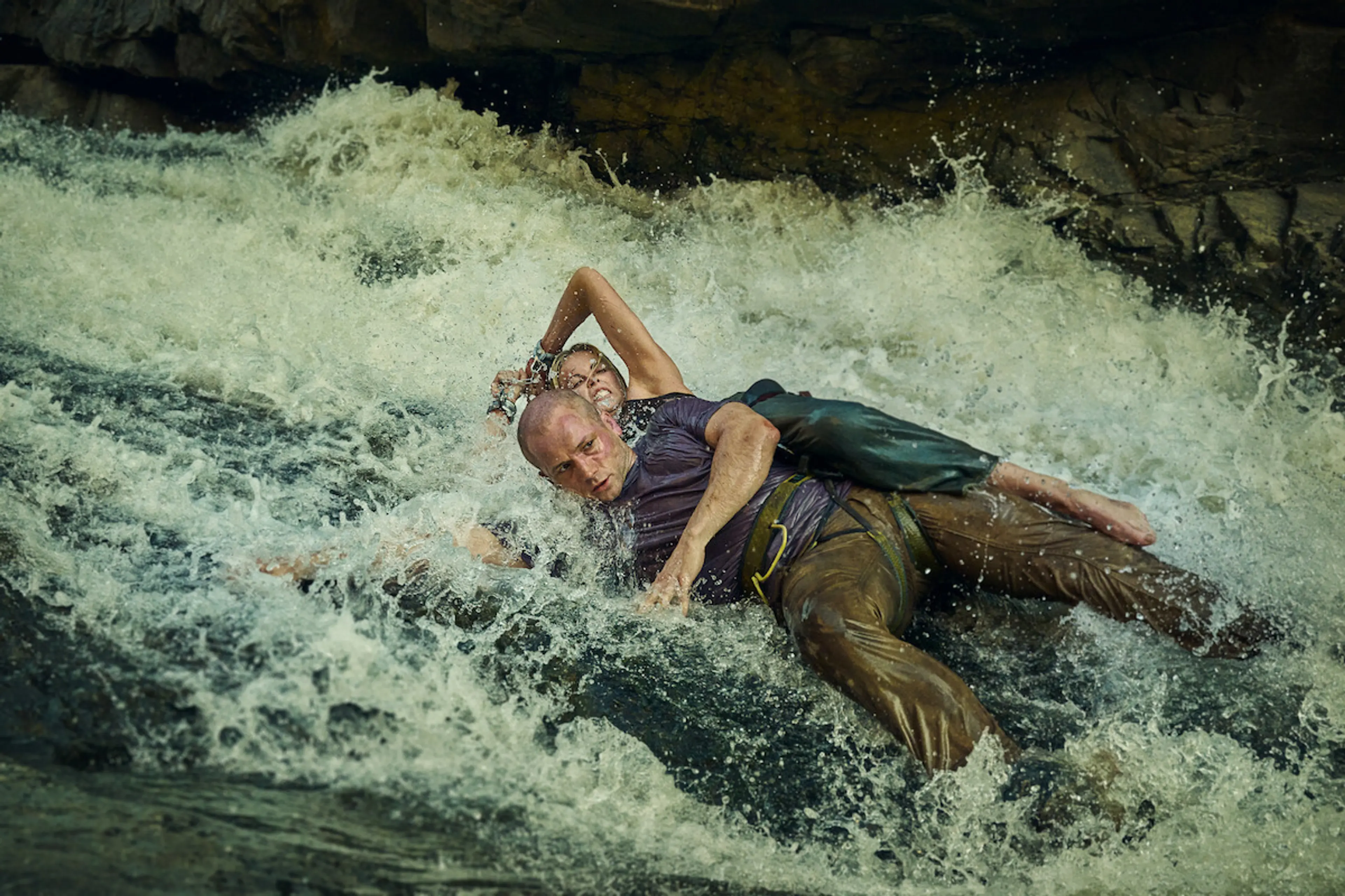 Sasha and Ben struggle in fast water beside rocks.