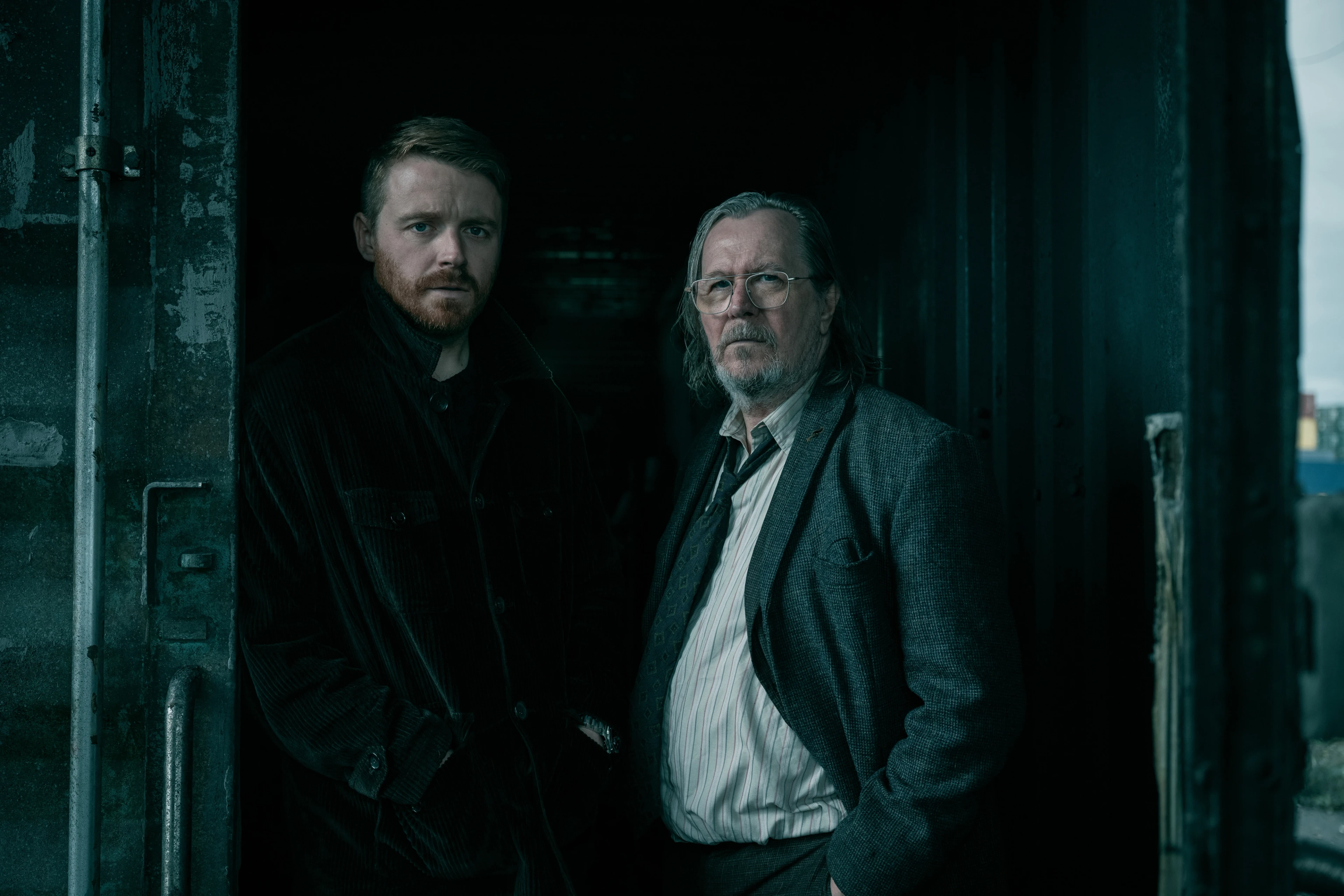 River Cartwright and Jackson Lamb stand beside each other in a dark doorway.