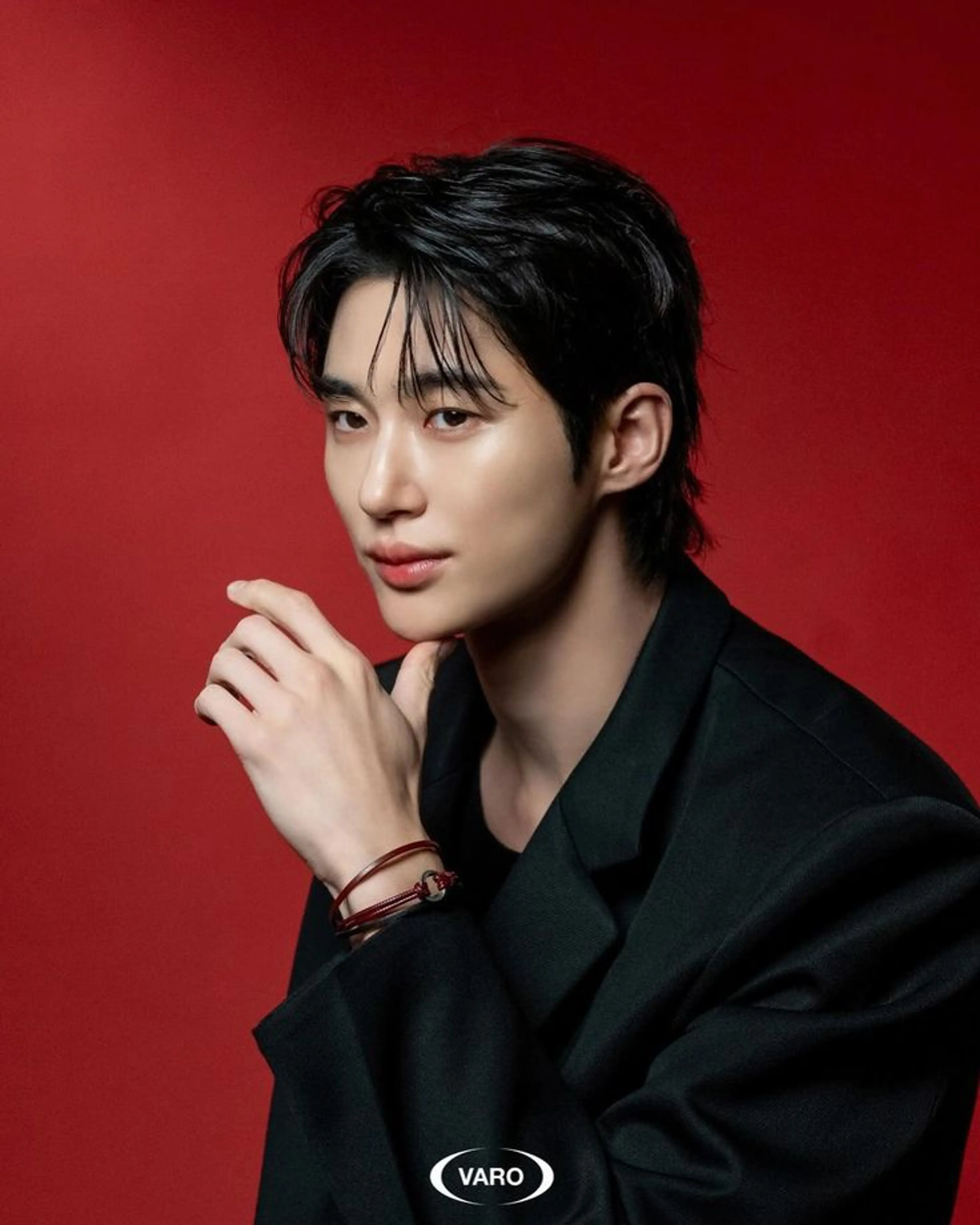 Byeon Woo-seok in a black suit against a red background, with the VARO logo visible.